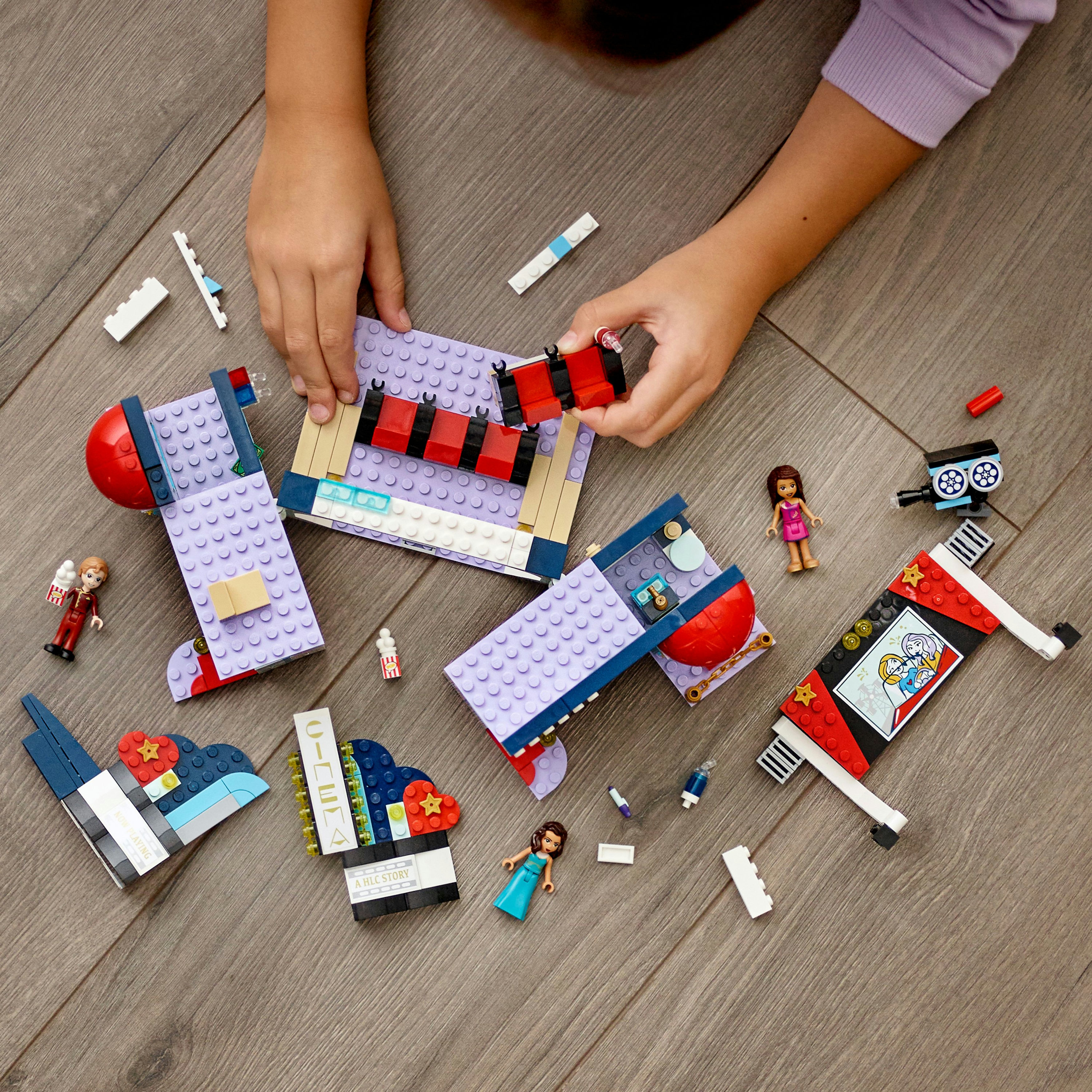 Manos de niño montando un set Lego Friends sobre una superficie de madera.