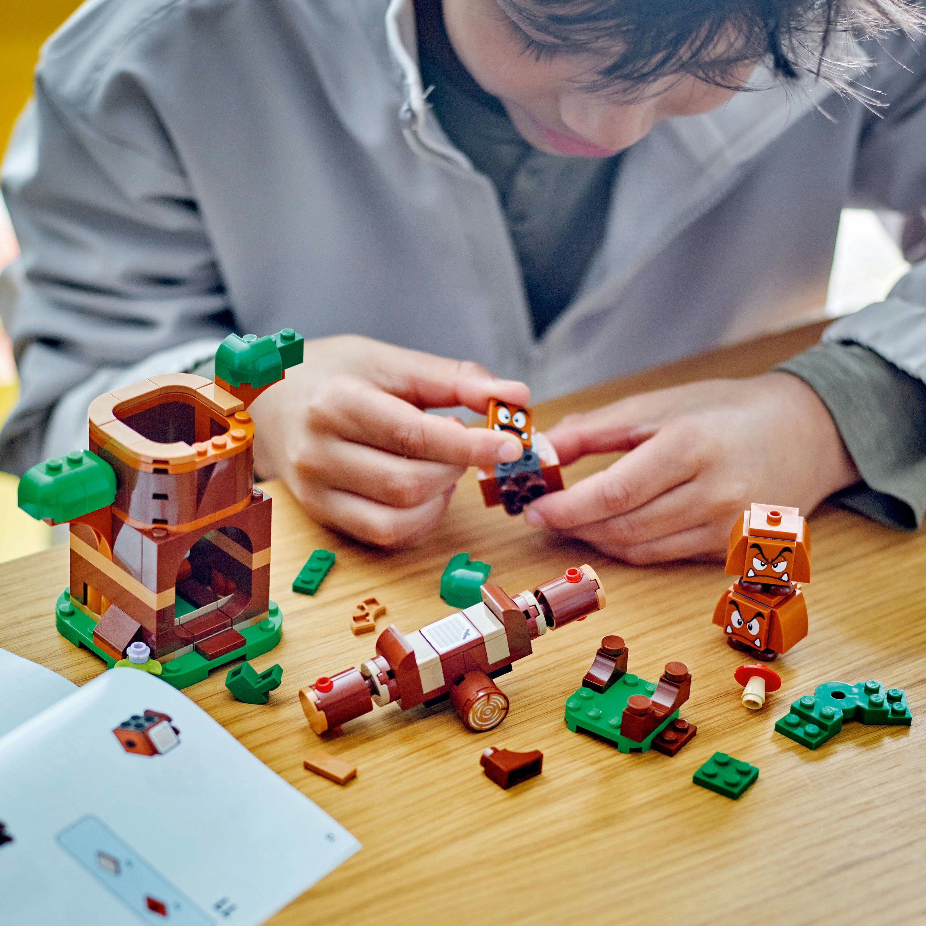 Ein Kind baut ein LEGO Super Mario Set zusammen, mit verschiedenen Komponenten und einer Bauanleitung.