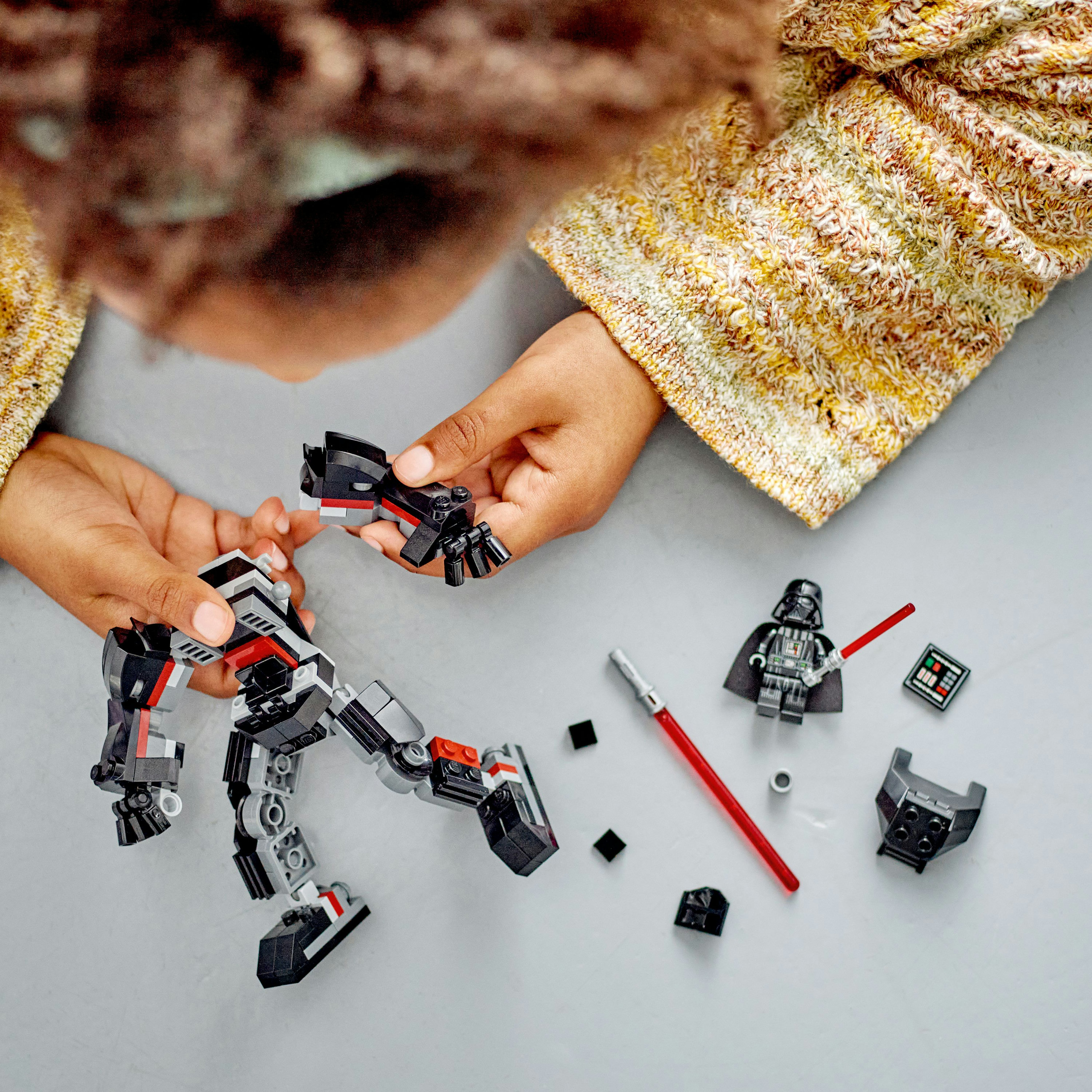 Ein Kind baut ein Lego Star Wars Set zusammen. Darth Vader und andere Teile liegen auf dem Tisch.