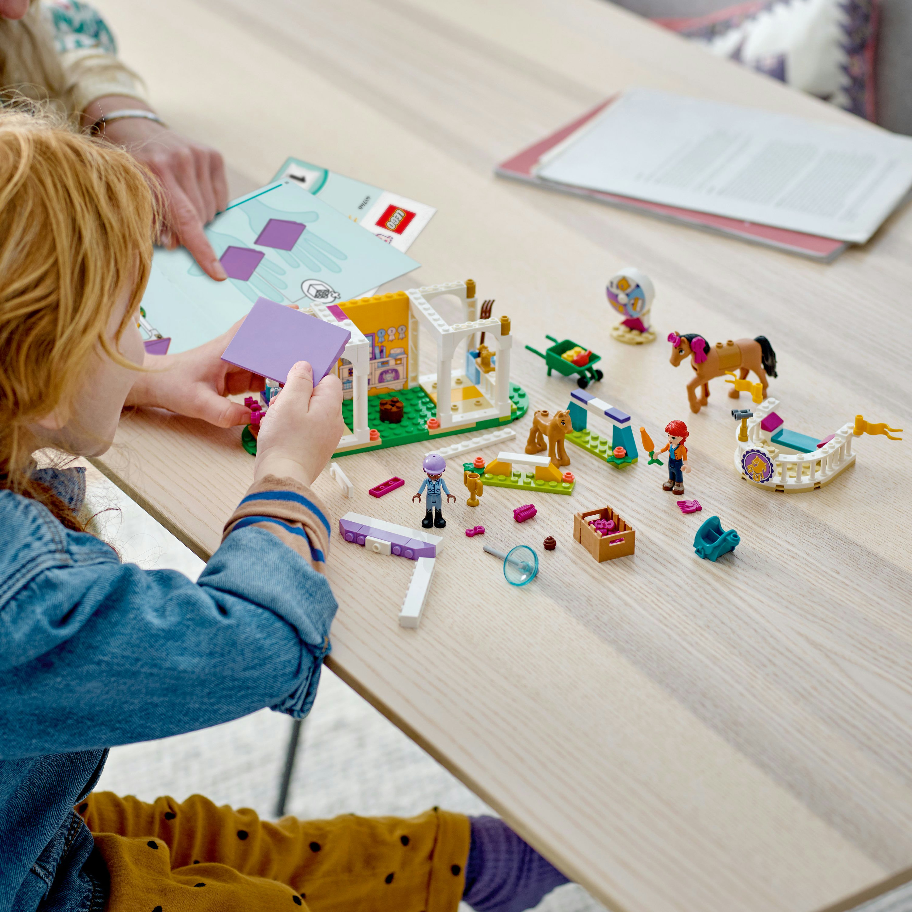 Kind und Erwachsener bauen LEGO Friends Set auf einem Tisch.