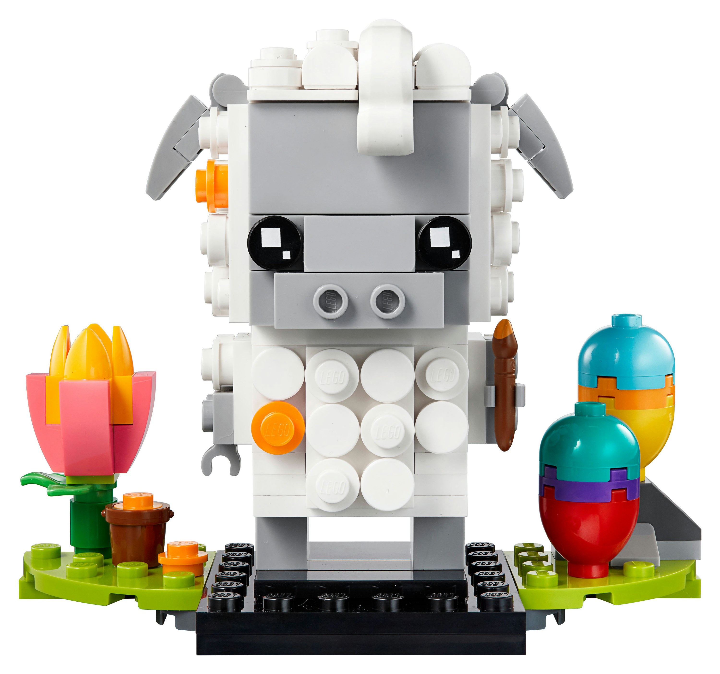 Una figurina di pecora Lego. Ha un corpo bianco, una testa grigia ed è su una base verde con fiori.