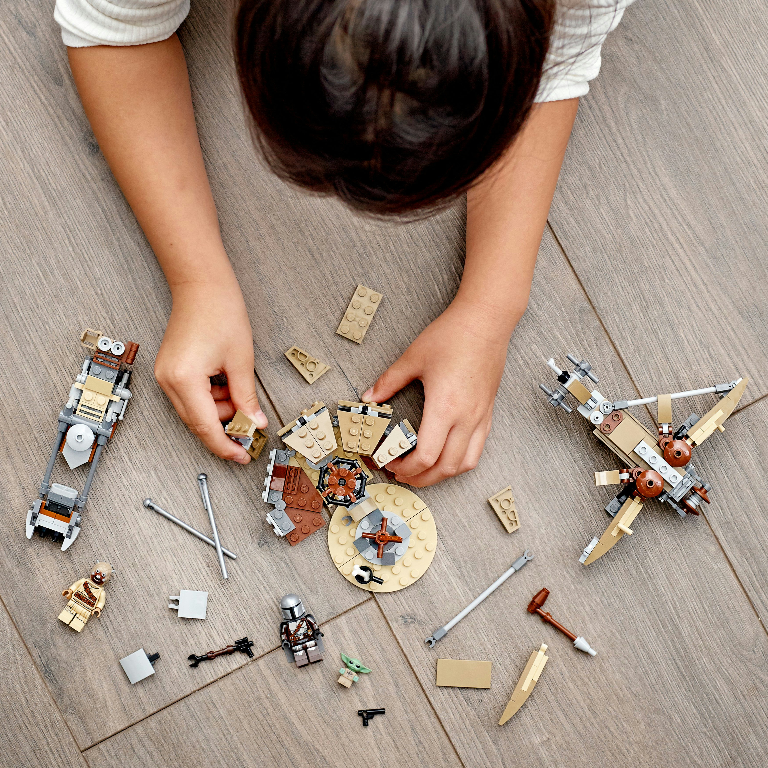 Bambino che gioca con set Lego Star Wars, inclusi landspeeder, personaggi e altri componenti.