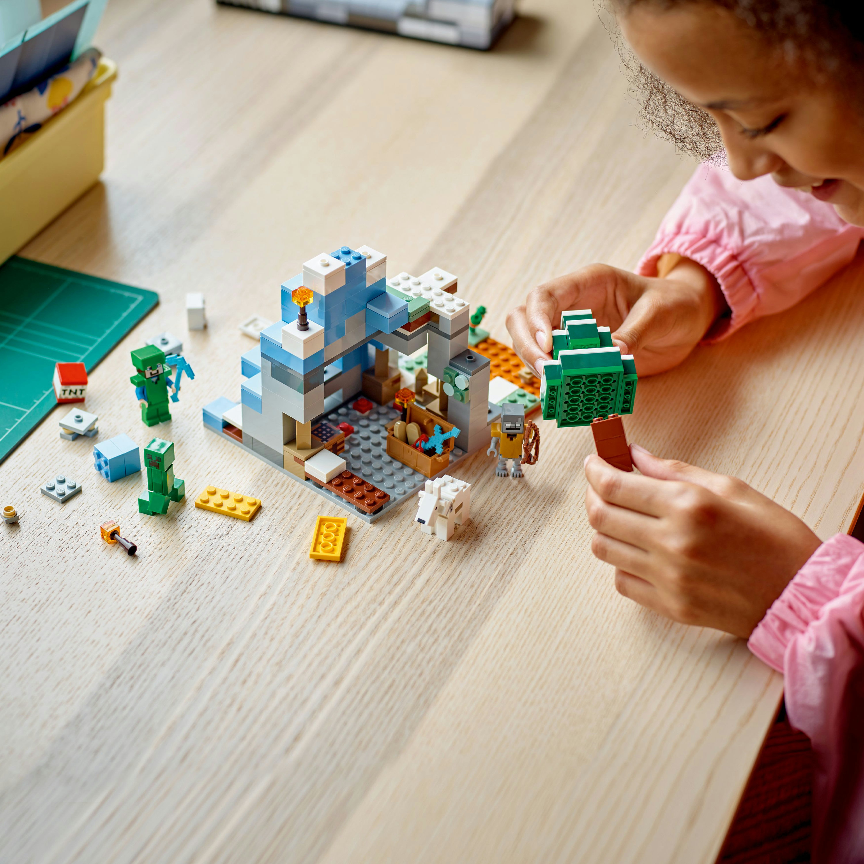 Ein Kind baut eine Lego Minecraft-Szene mit mehreren Lego-Figuren.