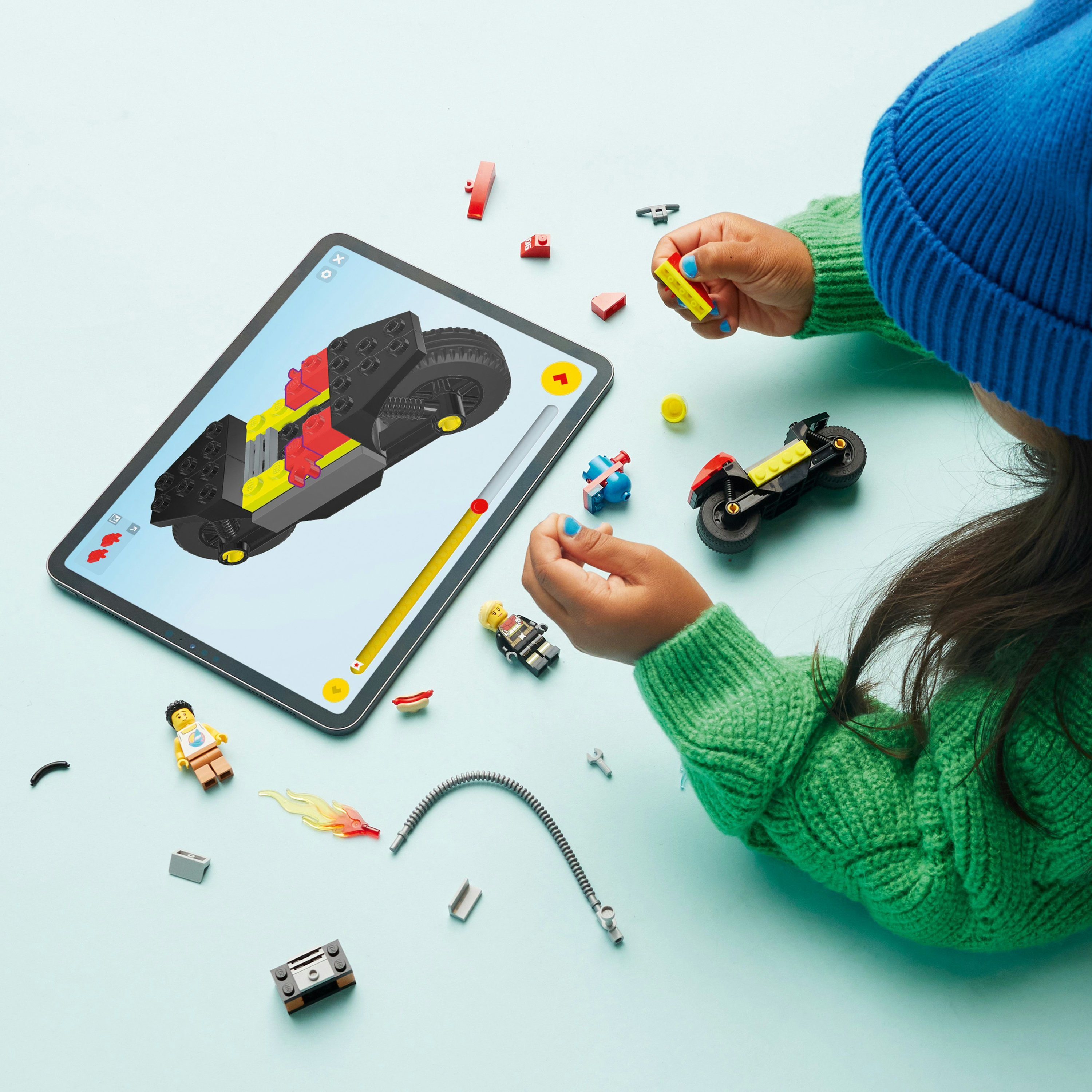 Dziecko używa tabletu z instrukcjami Lego do budowy zestawu motocykla Lego.