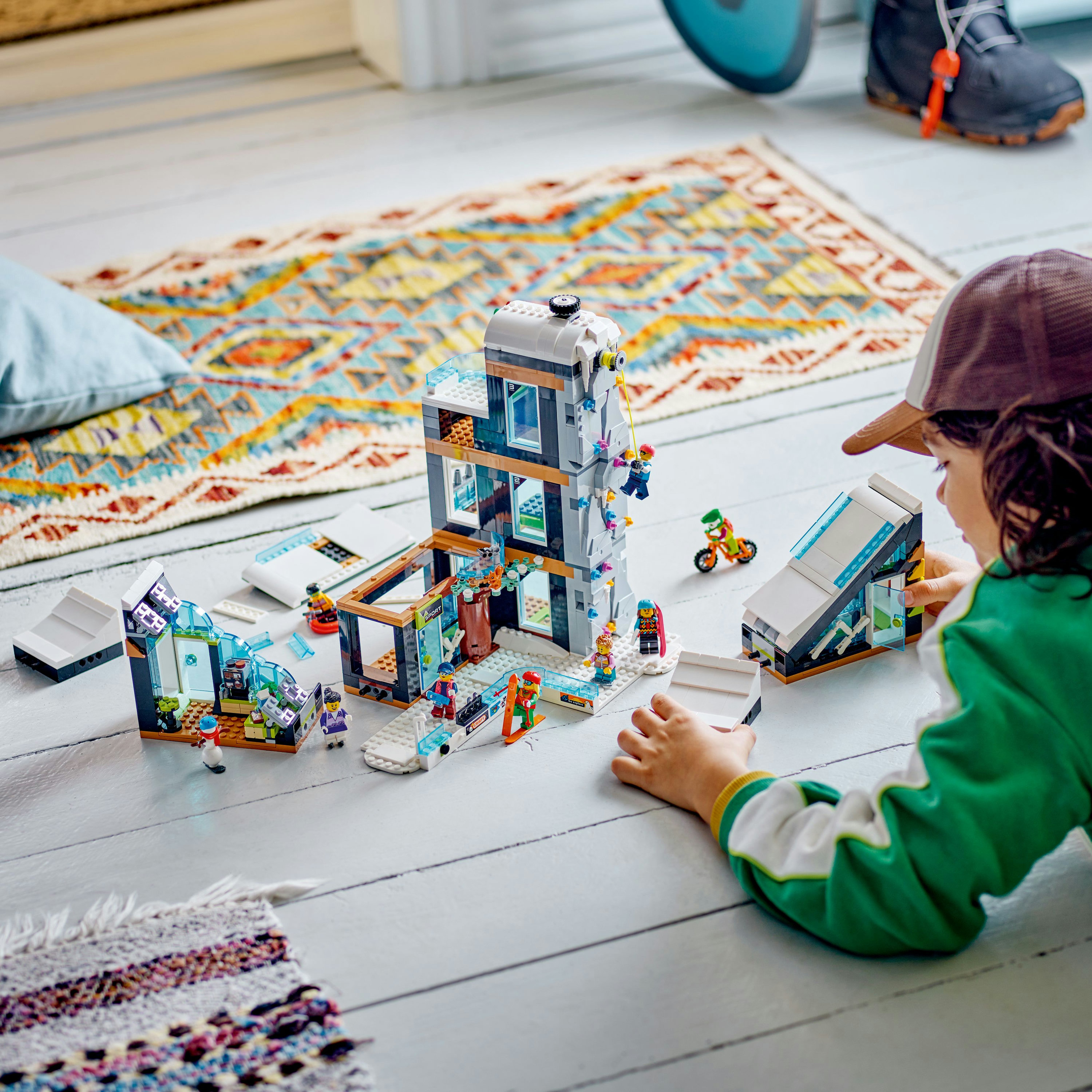 Un bambino che gioca con un set Lego raffigurante un edificio e altri pezzi Lego.