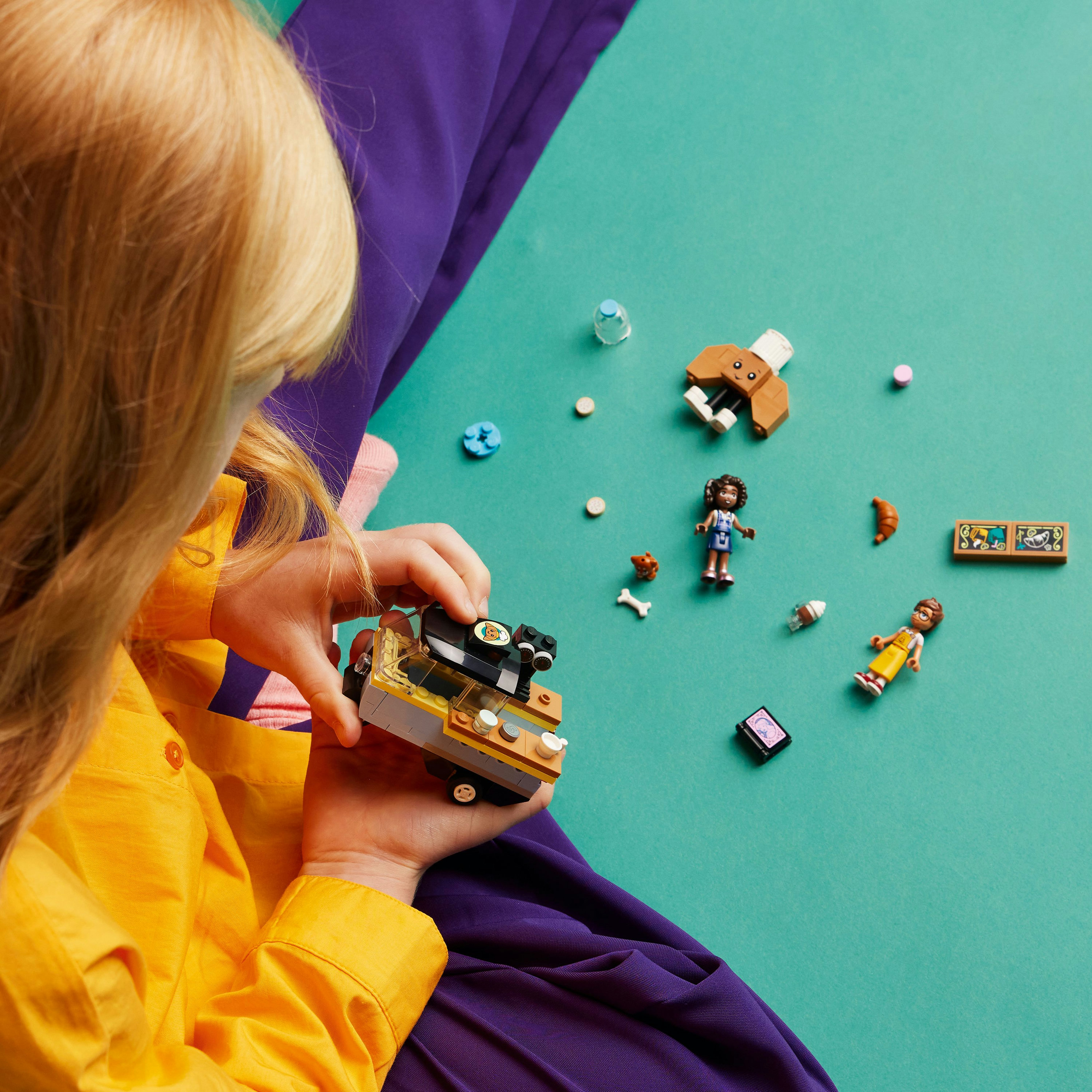 Een meisje speelt met Lego Friends set. Toont een foodtruck, minifiguren en accessoires.
