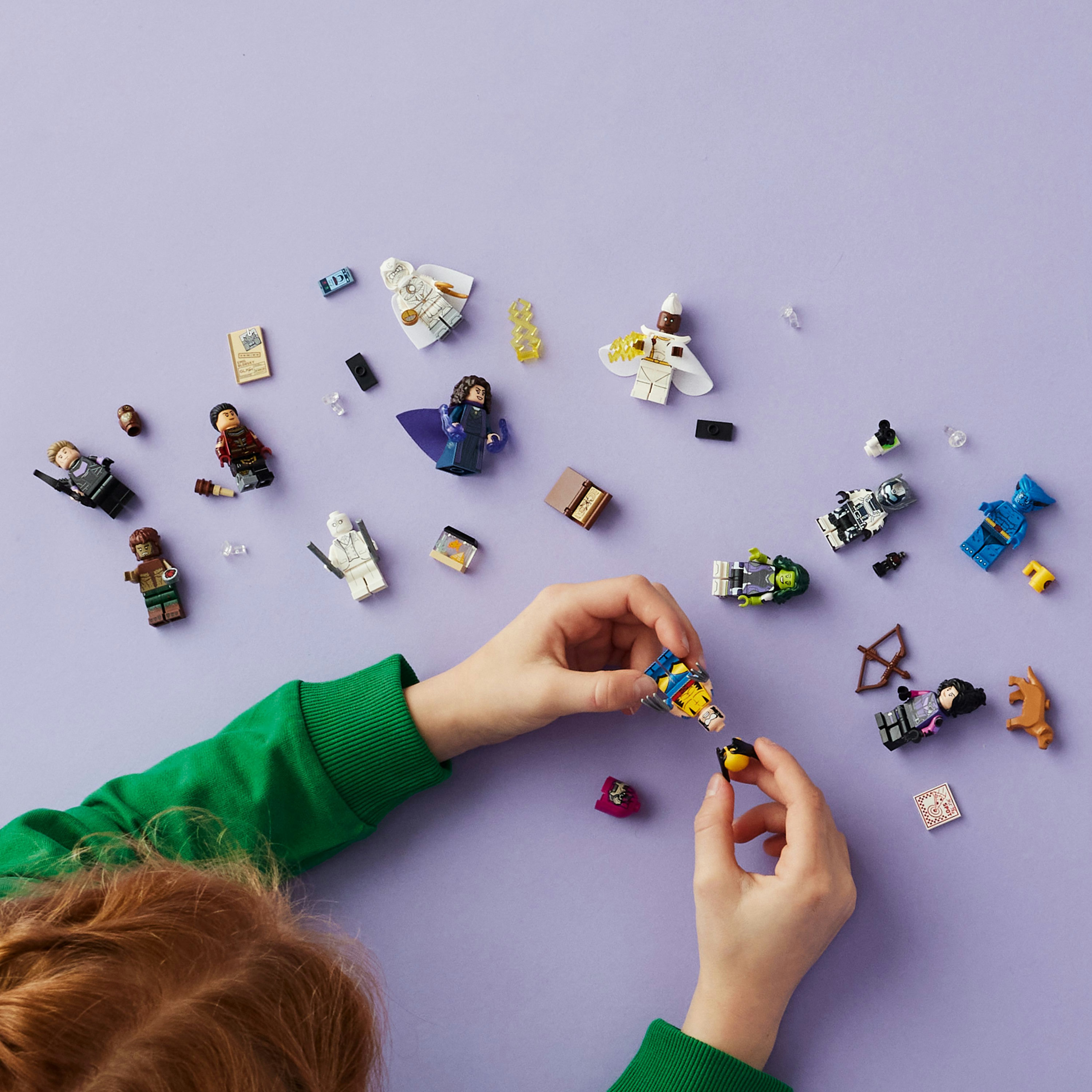 Minifigure e accessori Lego su superficie viola, mani che assemblano.