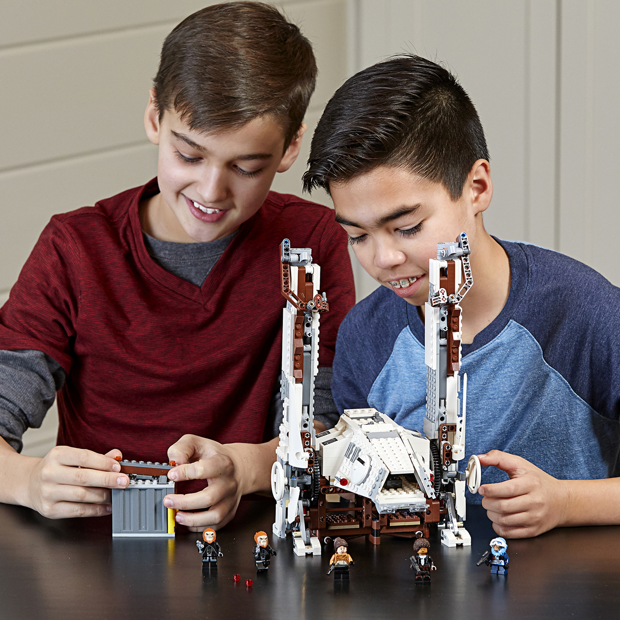 Dwóch chłopców budujących zestaw LEGO Star Wars. Kilka figurek i statek kosmiczny są widoczne.