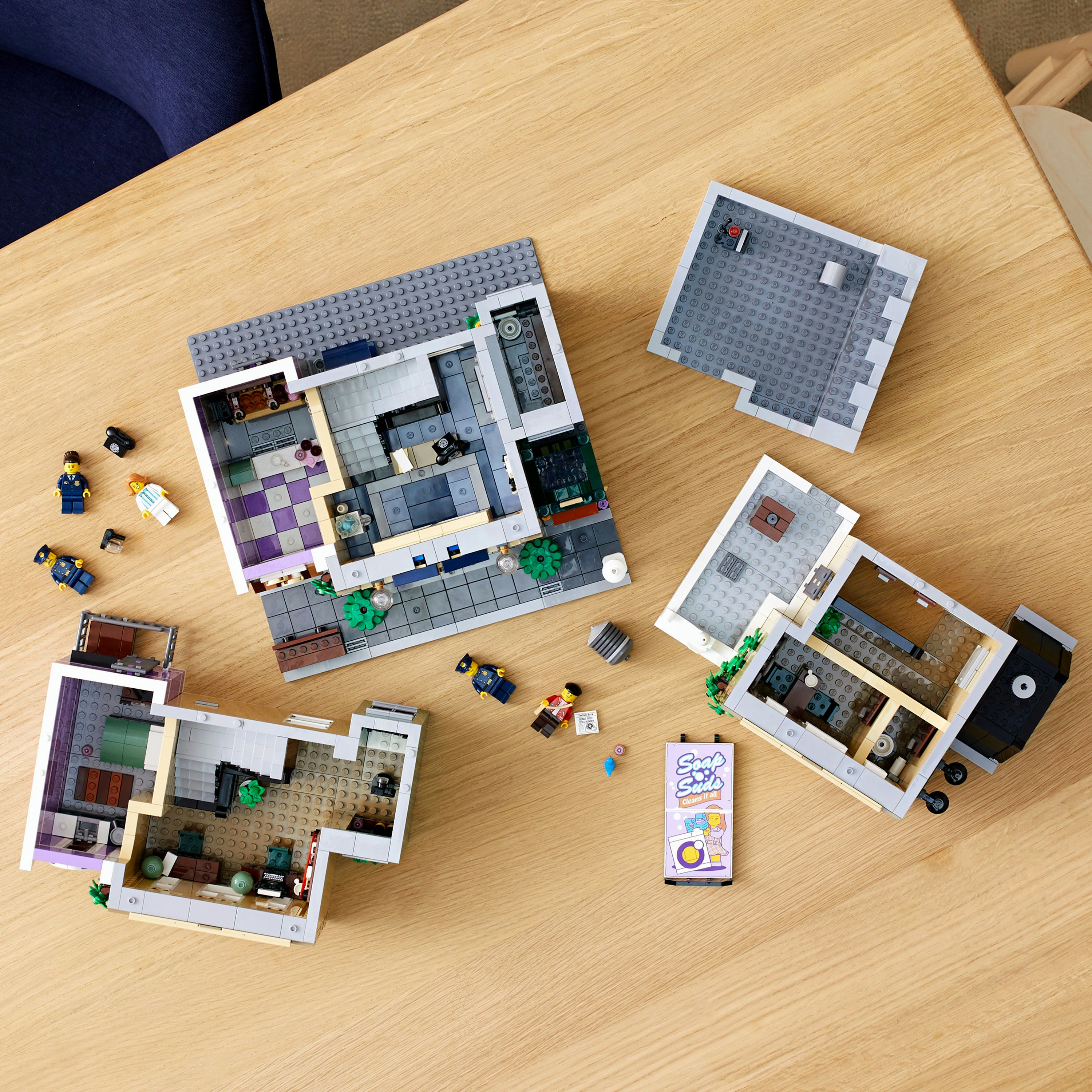 Drewniany stół z budynkami Lego w różnych fazach.