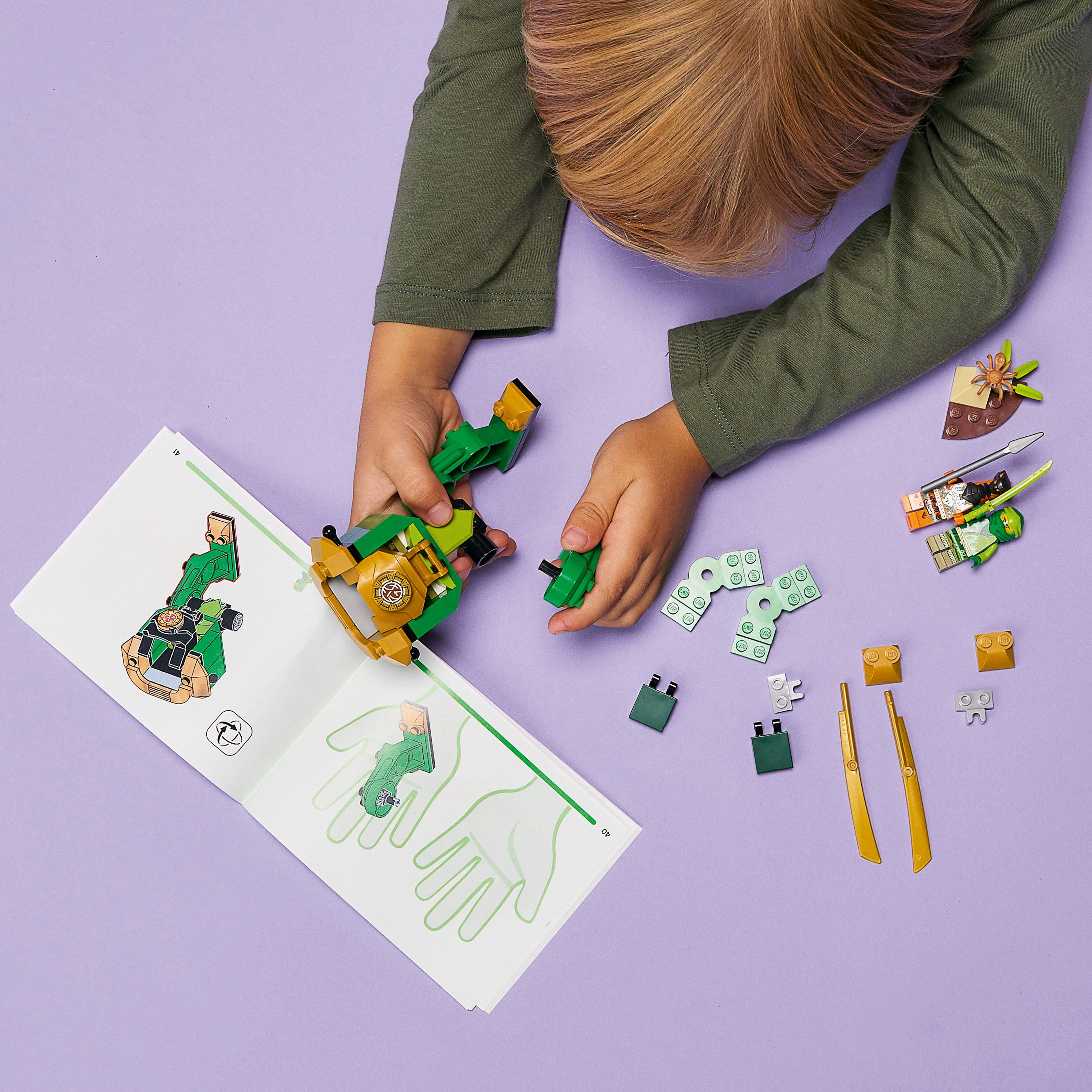 Un niño está construyendo un set LEGO. El set incluye una figura de ninja verde y un libro.