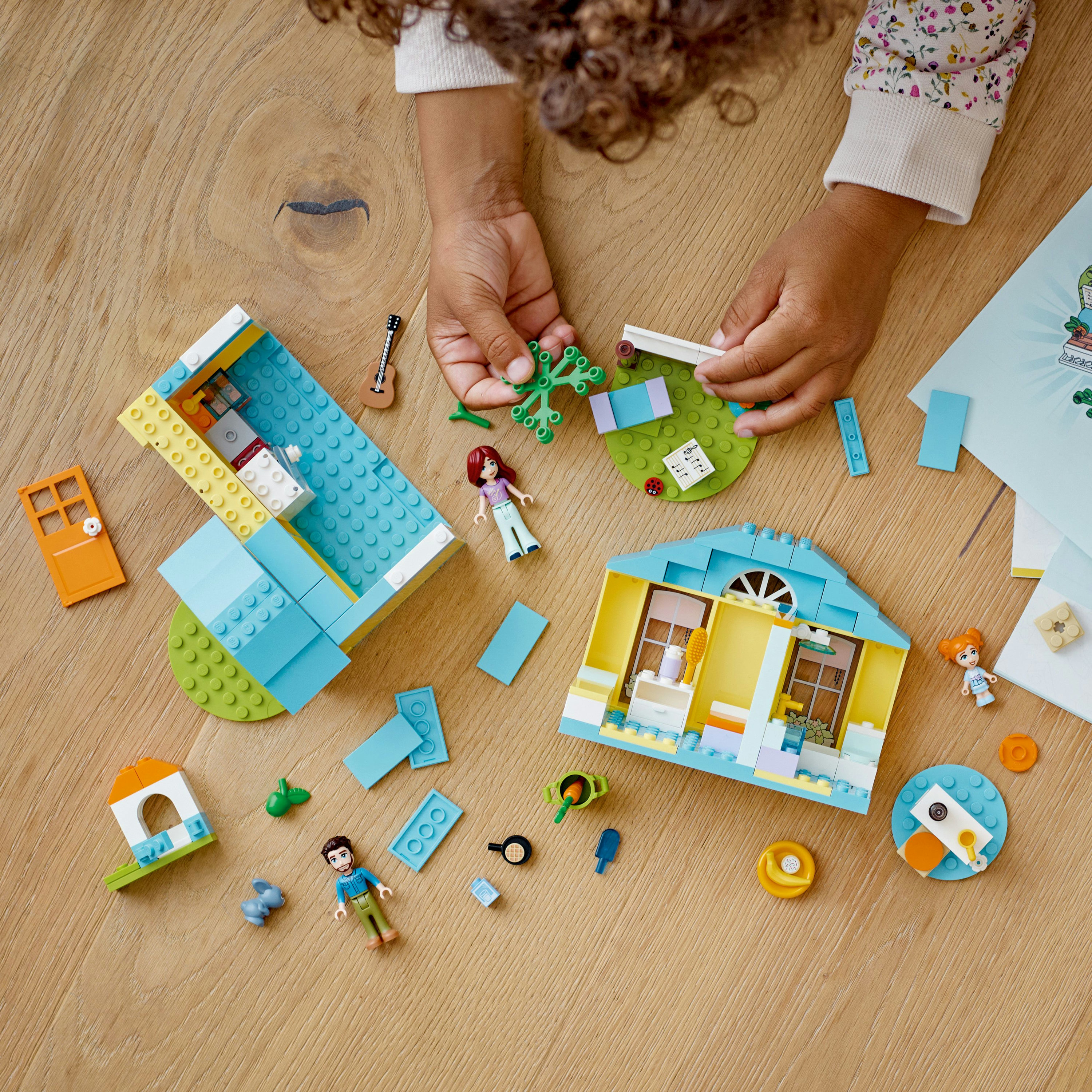 Kind baut ein Lego Friends Haus zusammen, einschließlich Figuren und verschiedener Lego-Komponenten.