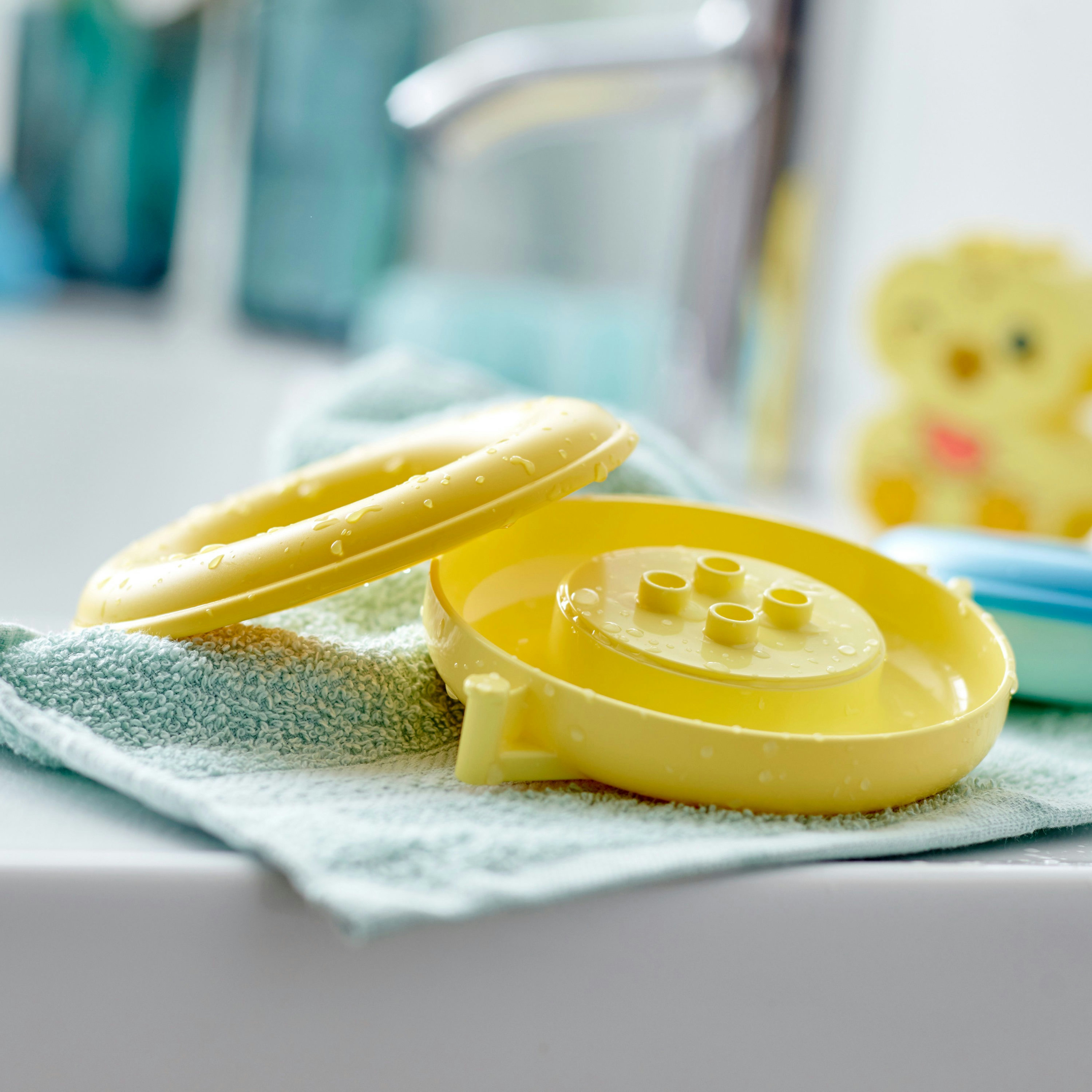 Żółte zabawki do kąpieli Lego na niebieskim ręczniku. Krople wody na zabawkach.