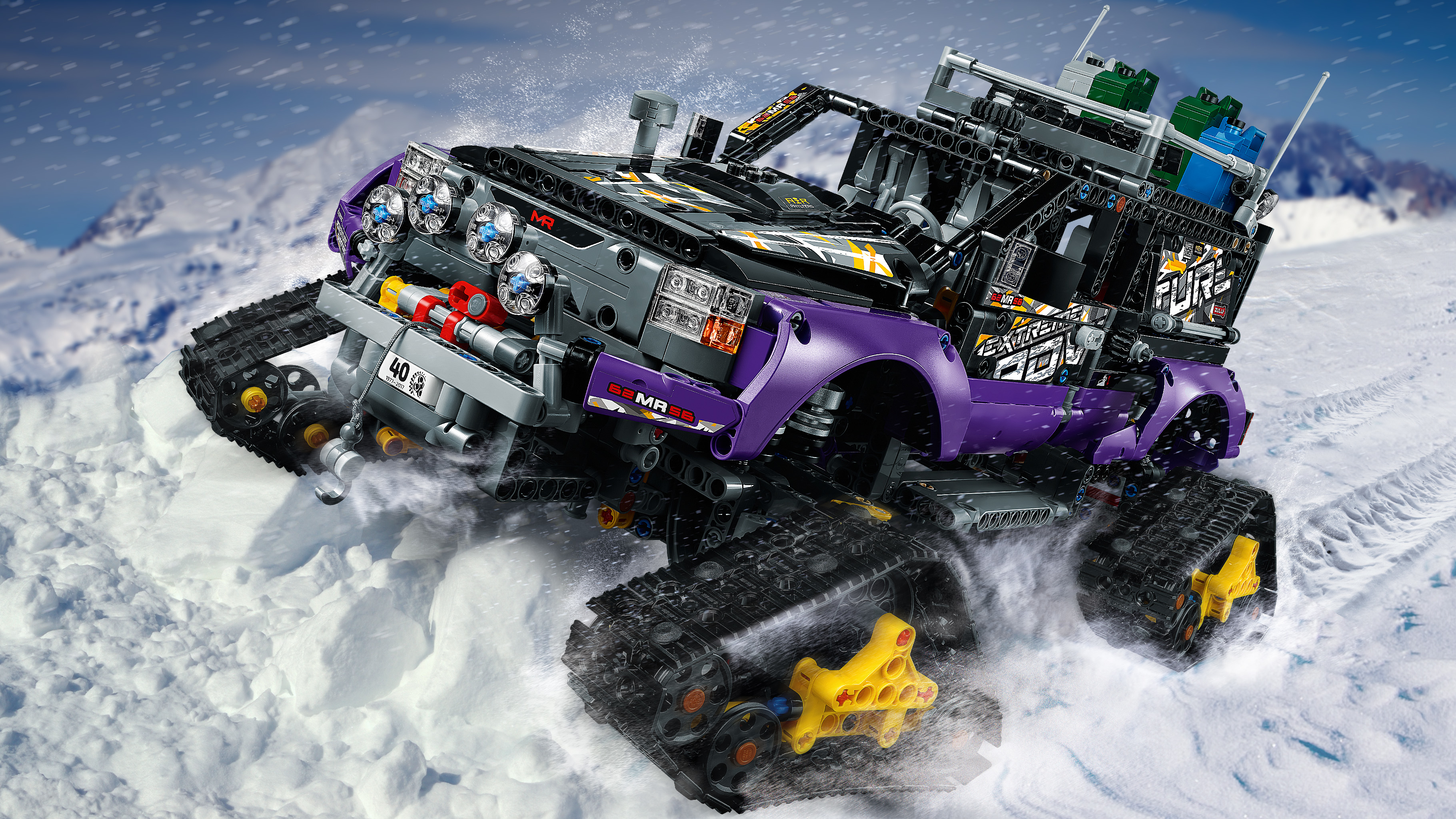 Ciężarówka Lego Technic Monster Truck jadąca po śniegu. Fioletowa ciężarówka z czarnymi gąsienicami i białym śniegiem.