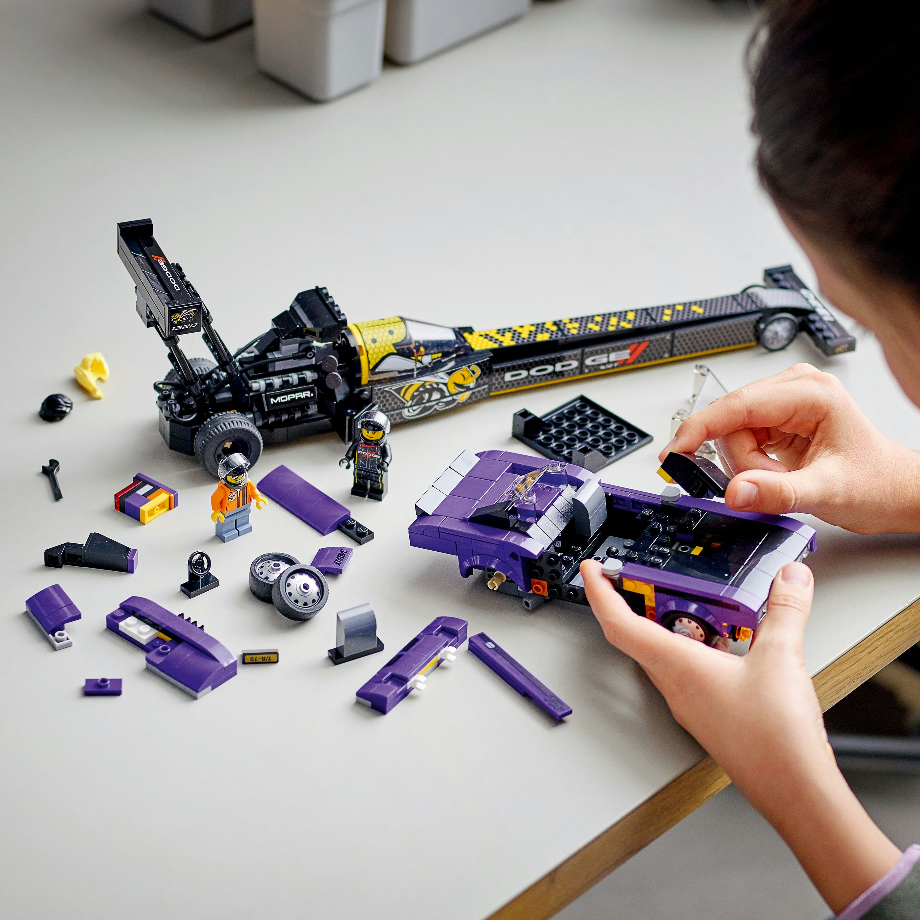Set Lego con dragster e camion viola, e minifigure. Su un tavolo.