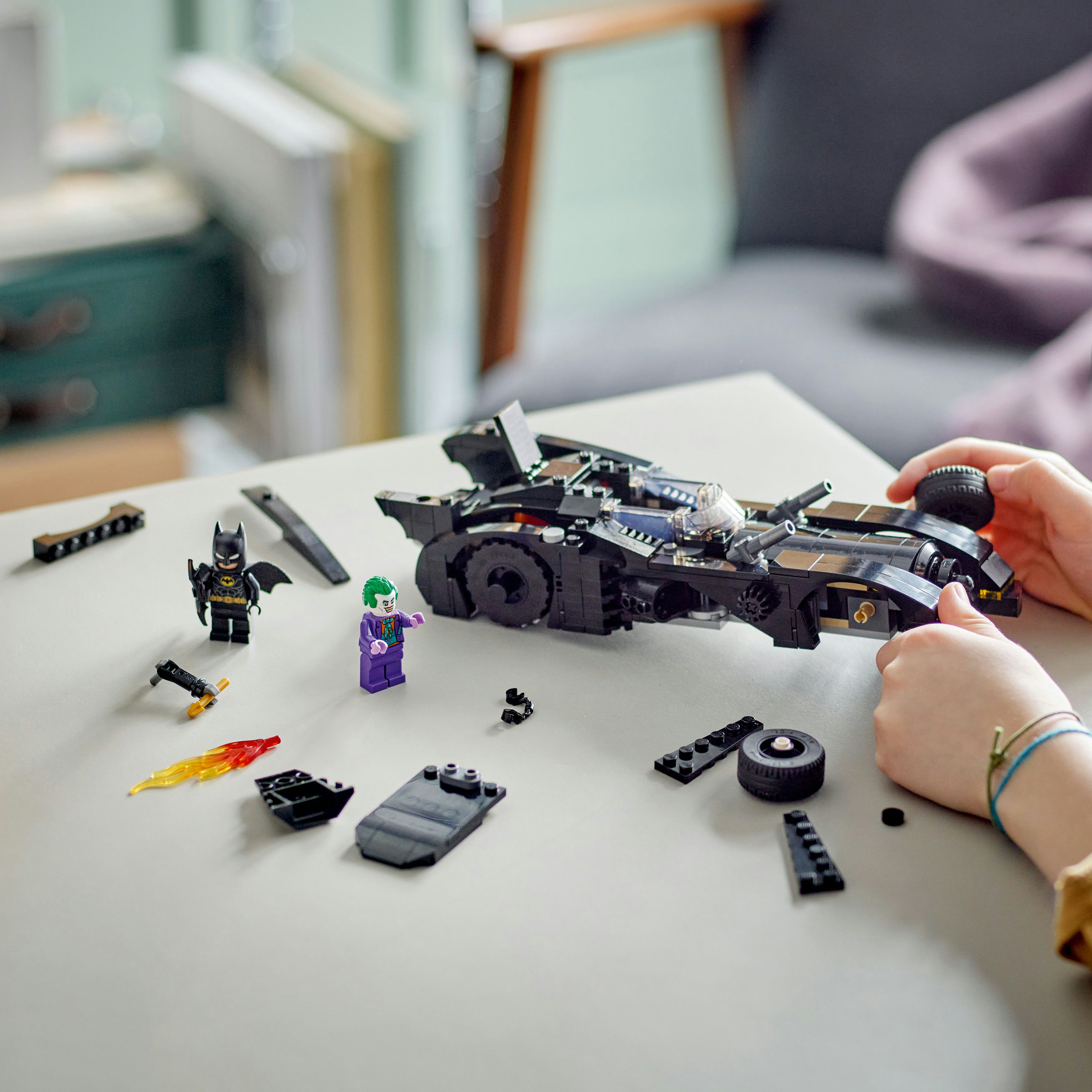 LEGO Batman Batmobil-Set mit Batman-, Joker-Figuren und Zubehör auf einem Tisch.