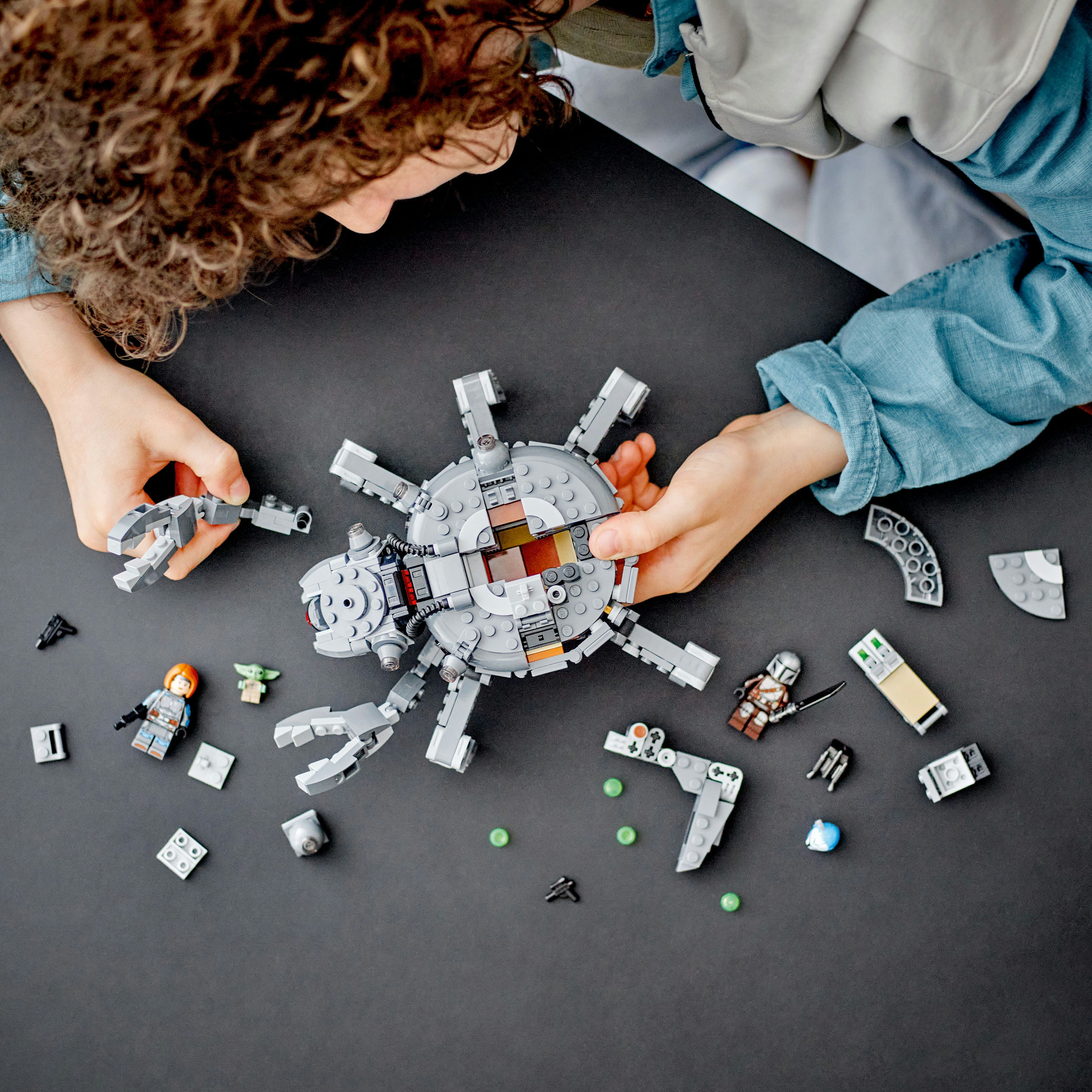 Lego Set mit Figuren, Hände bauen, auf dunklem Hintergrund.