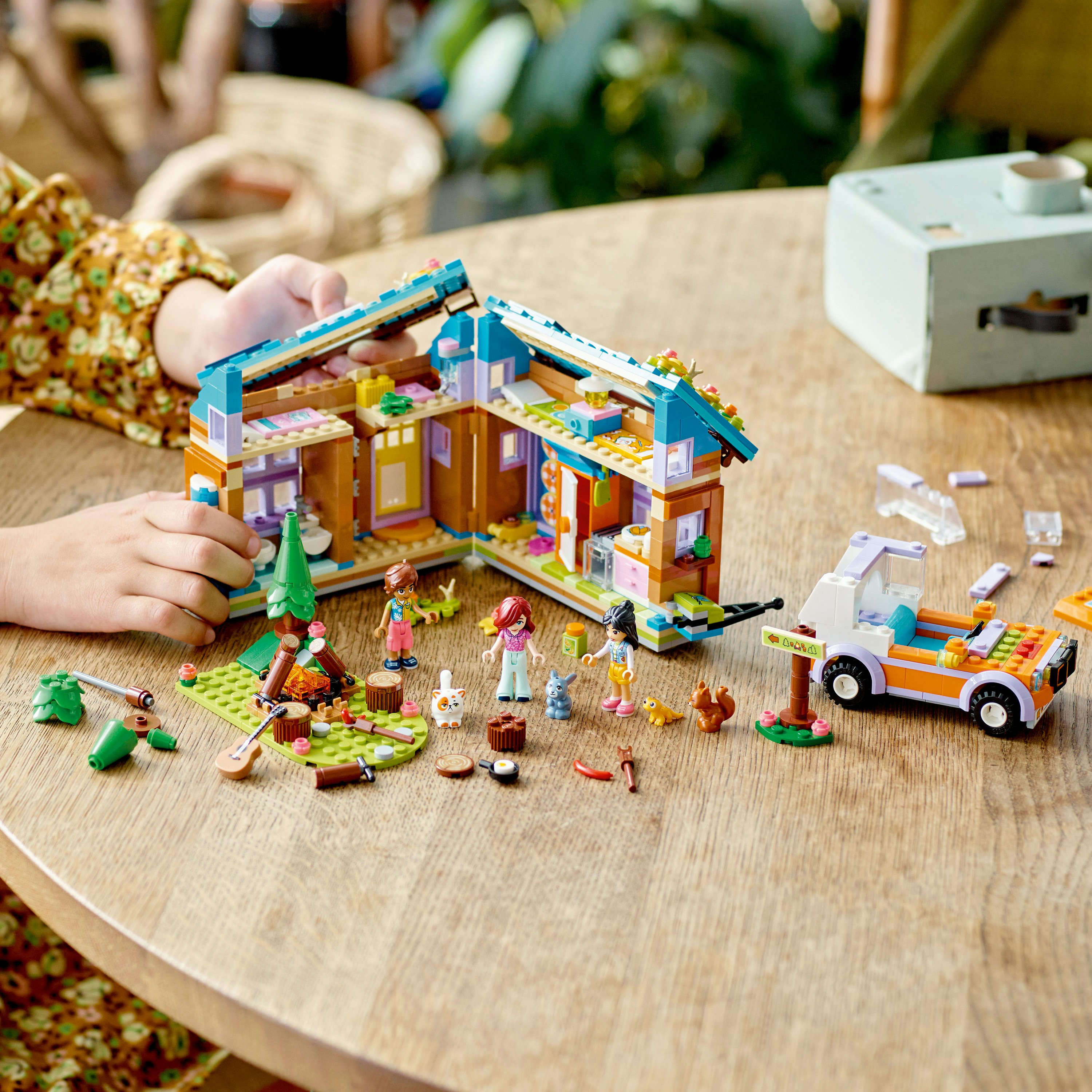 Set Lego Friends: casa, minifiguras y accesorios en una mesa de madera.