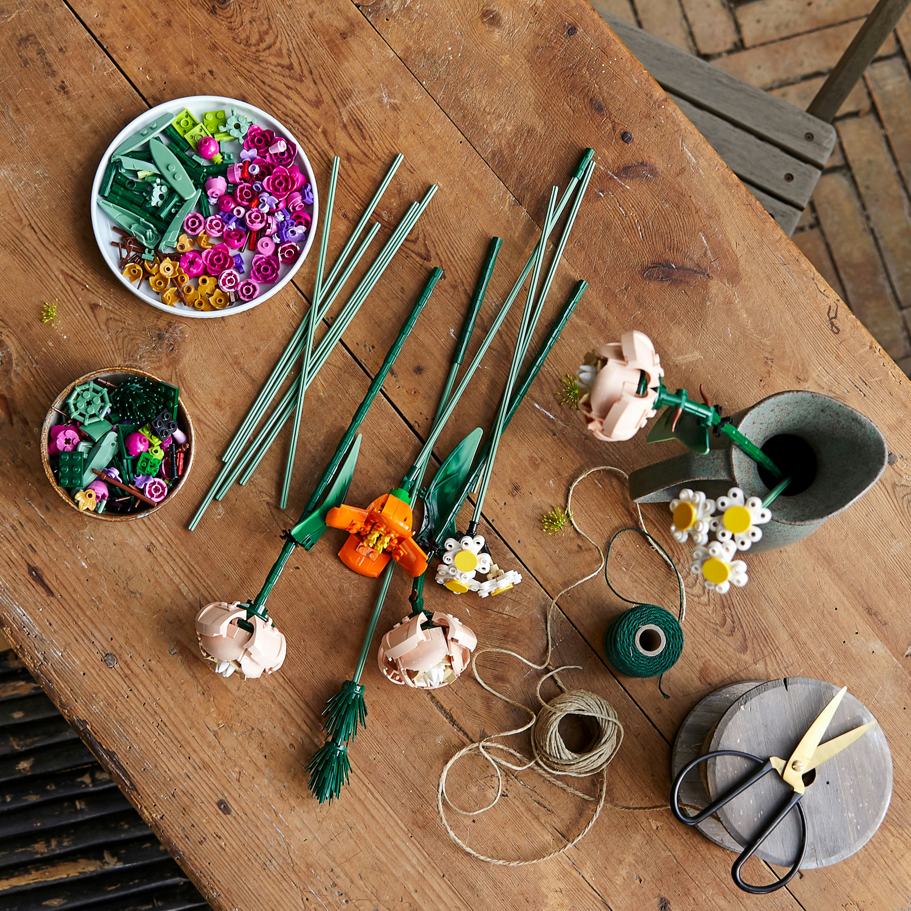 Flores Lego y accesorios sobre una mesa de madera.