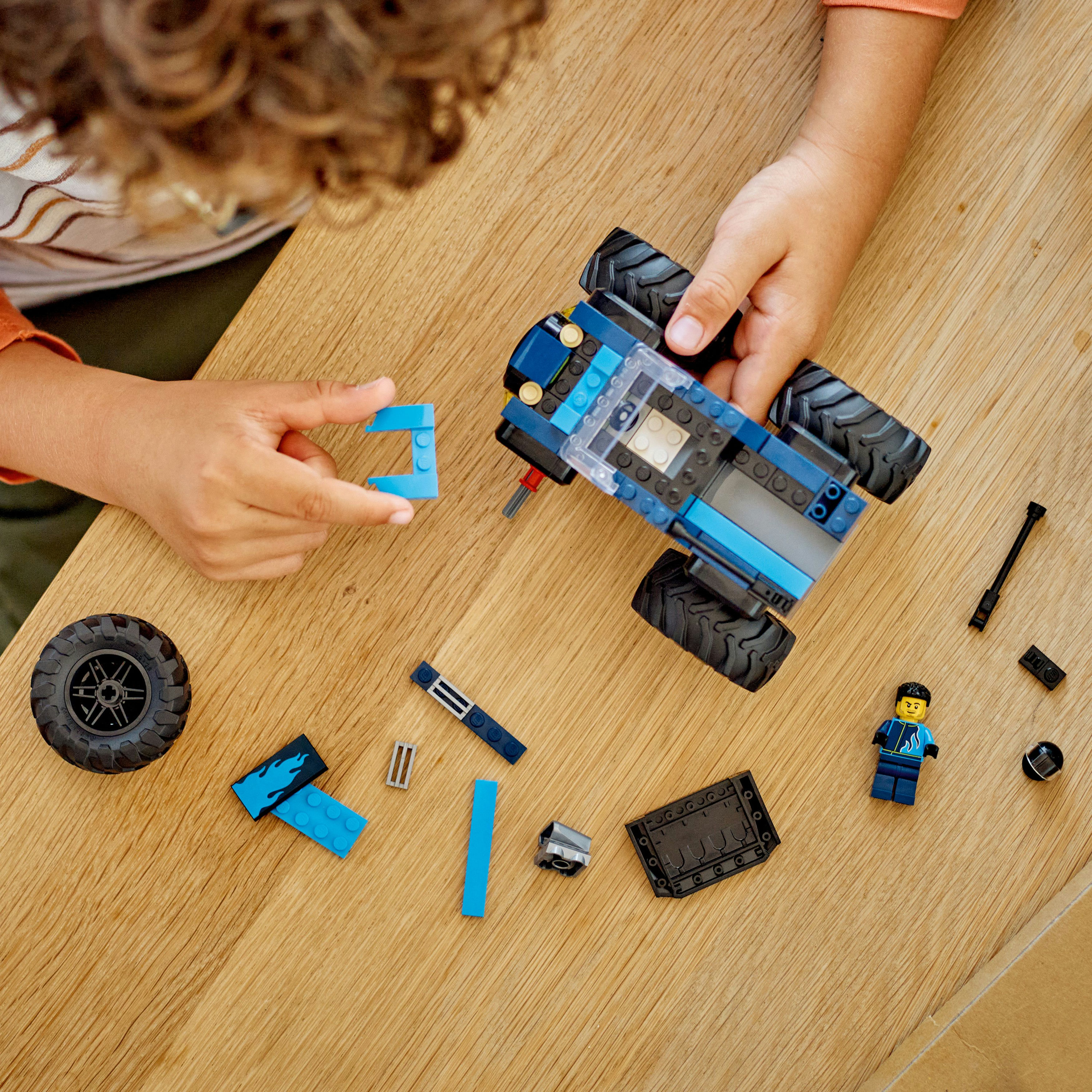 Bir çocuğun elleri, ahşap bir masada bir Lego kamyonu birleştiriyor, diğer Lego parçaları dağınık.