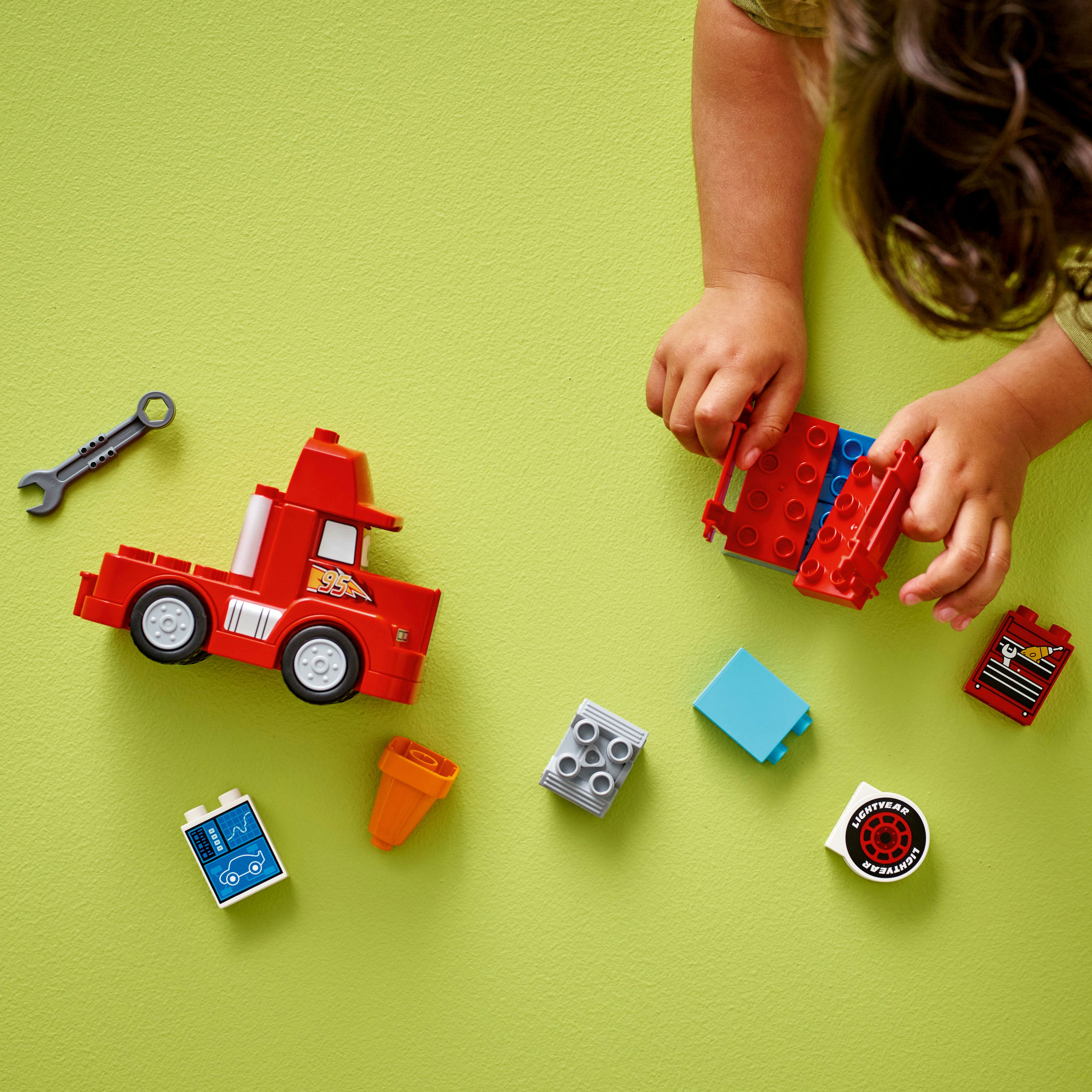 Kinderhanden met Lego stenen en een rode vrachtwagen.