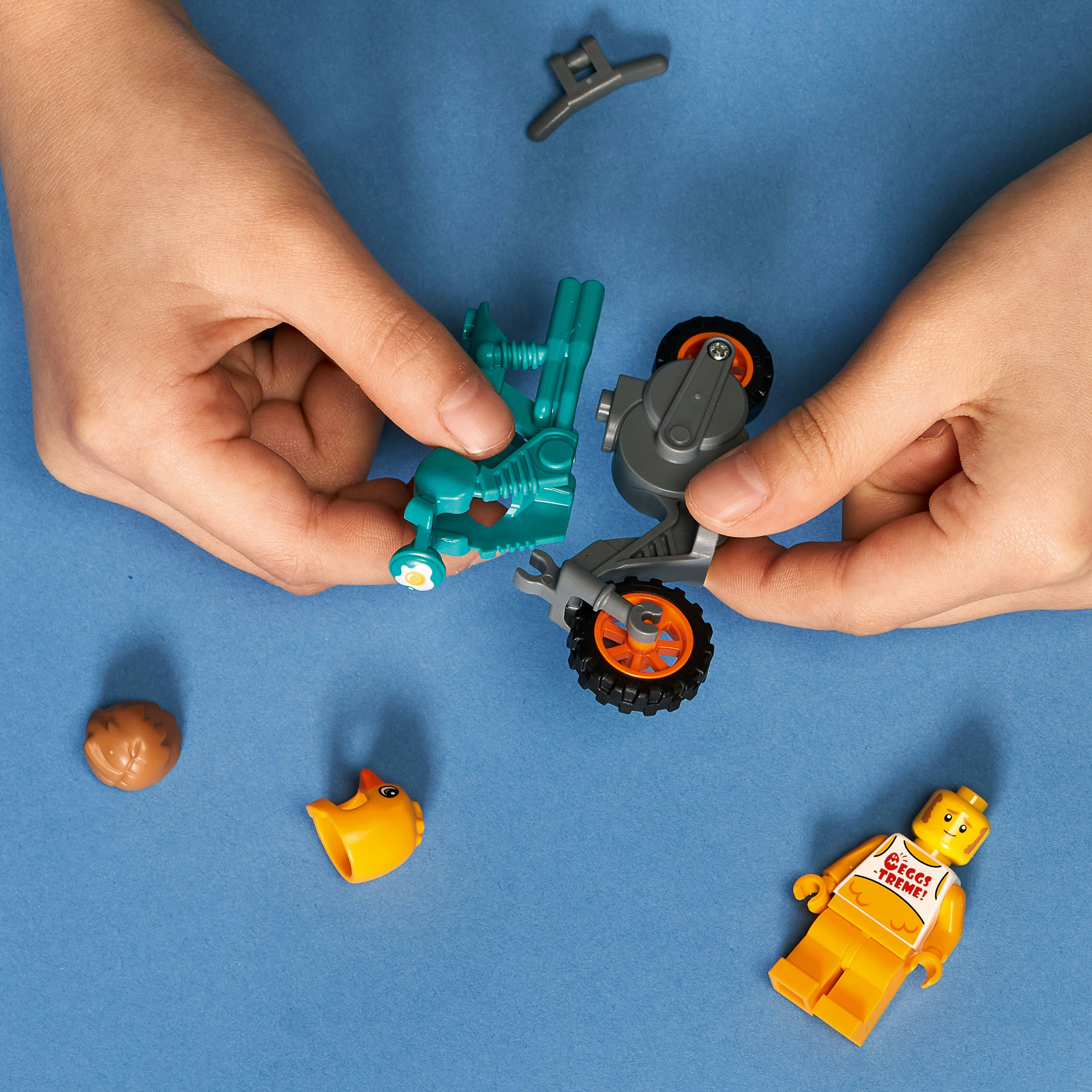 Kinderhände, die ein Lego-Set zusammenbauen, darunter ein Motorrad mit orangen Akzenten.
