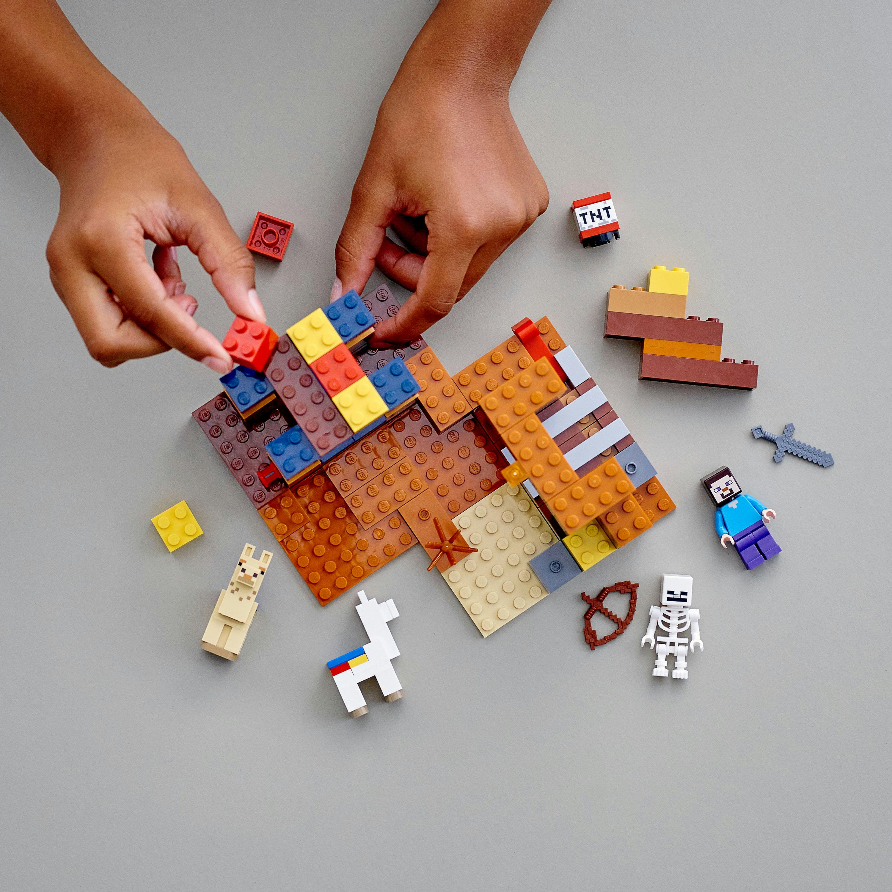 Eller, figürlerle bir Lego Minecraft sahnesi inşa ediyor.