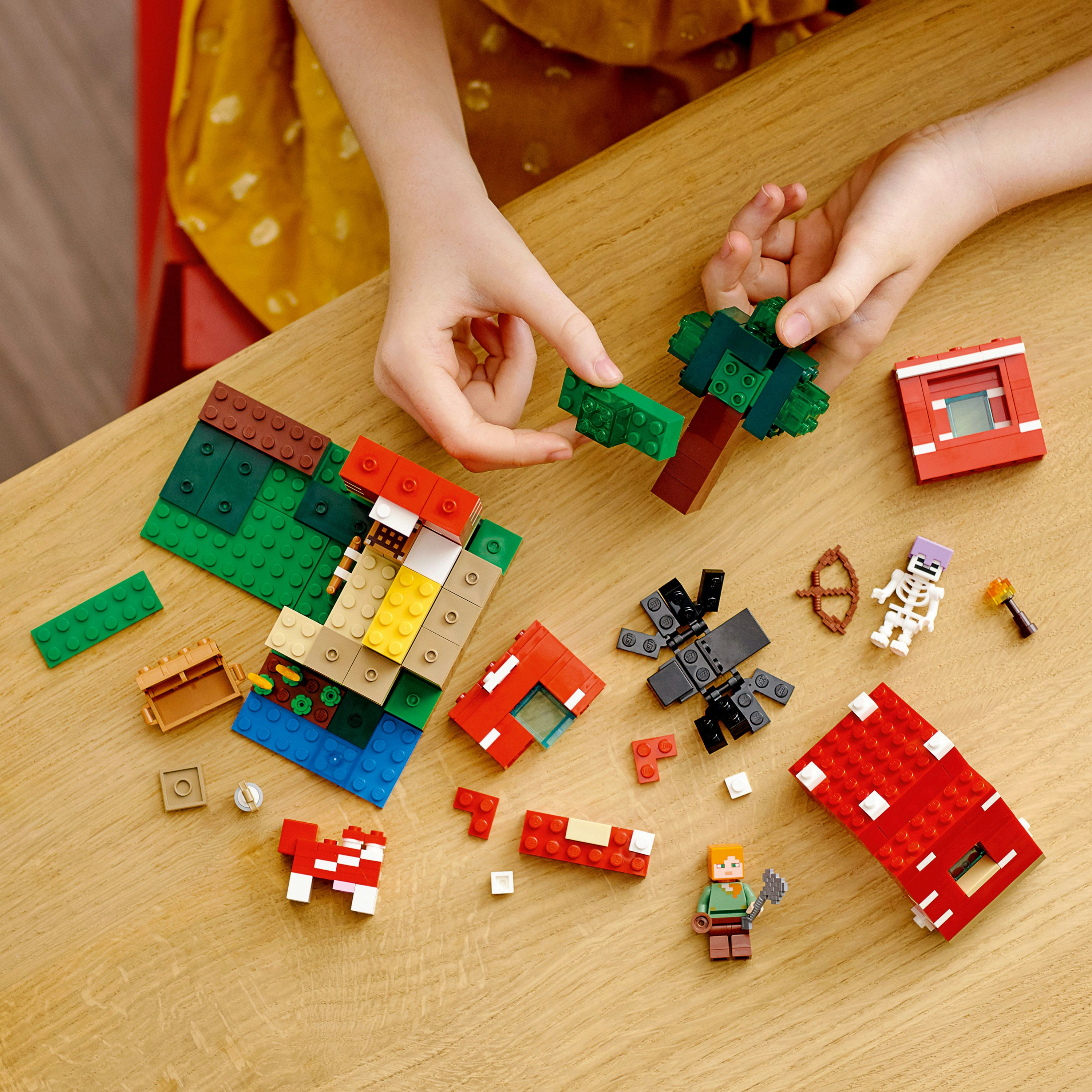 Ahşap masada Lego Minecraft seti. Figürler, bloklar ve kırmızı bir ev içerir.