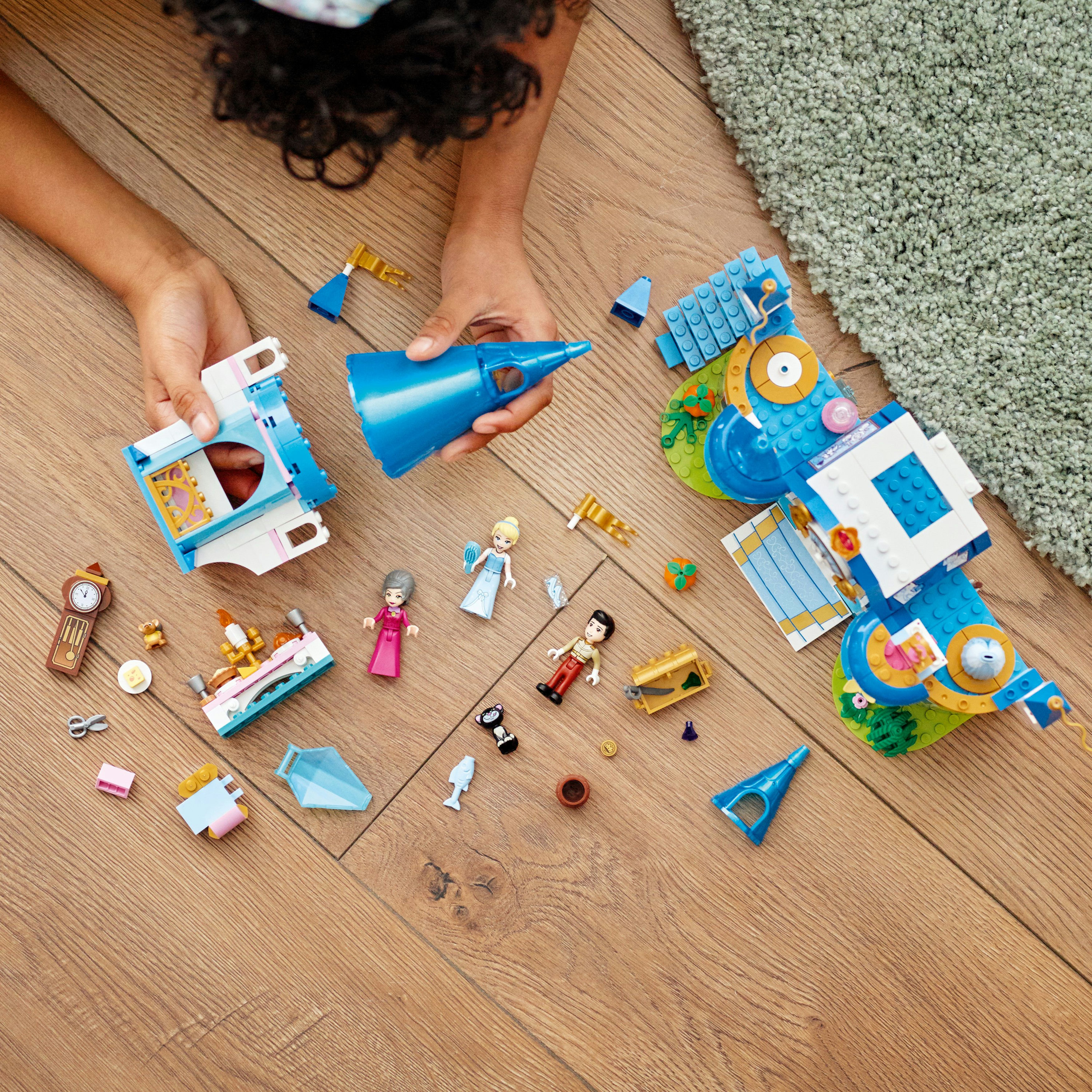 Handen van een kind die LEGO-stukken op een houten oppervlak monteren.