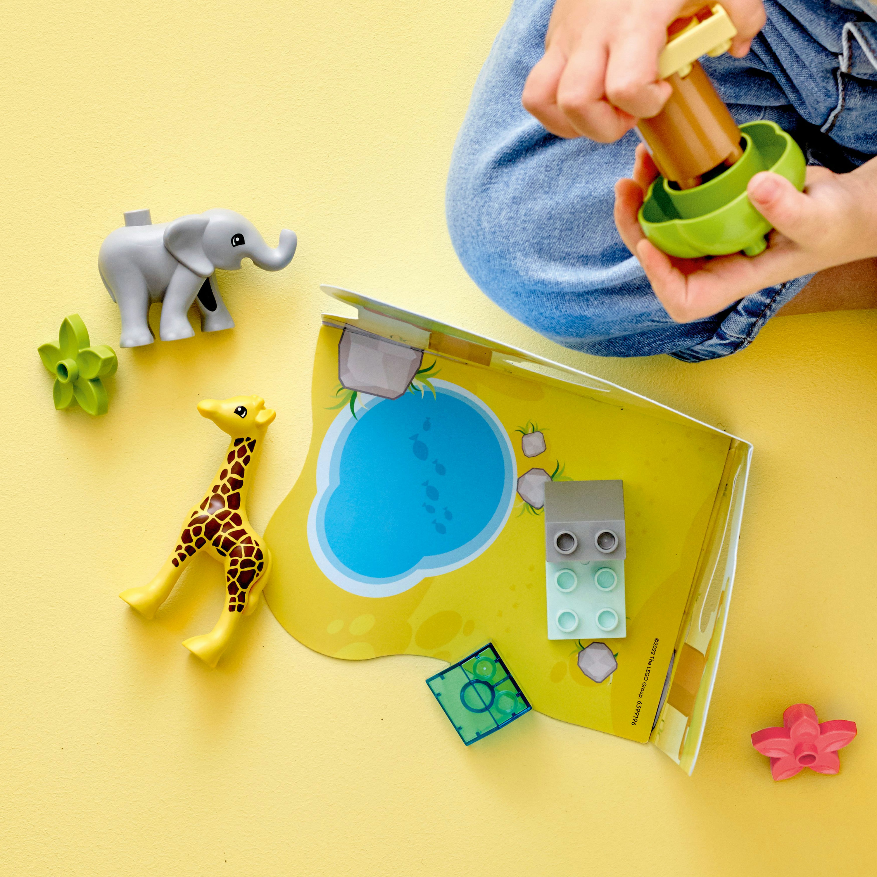 LEGO Duplo Set mit Tieren und einem Buch. Die Hände eines Kindes sind beim Hinzufügen eines Teils sichtbar.