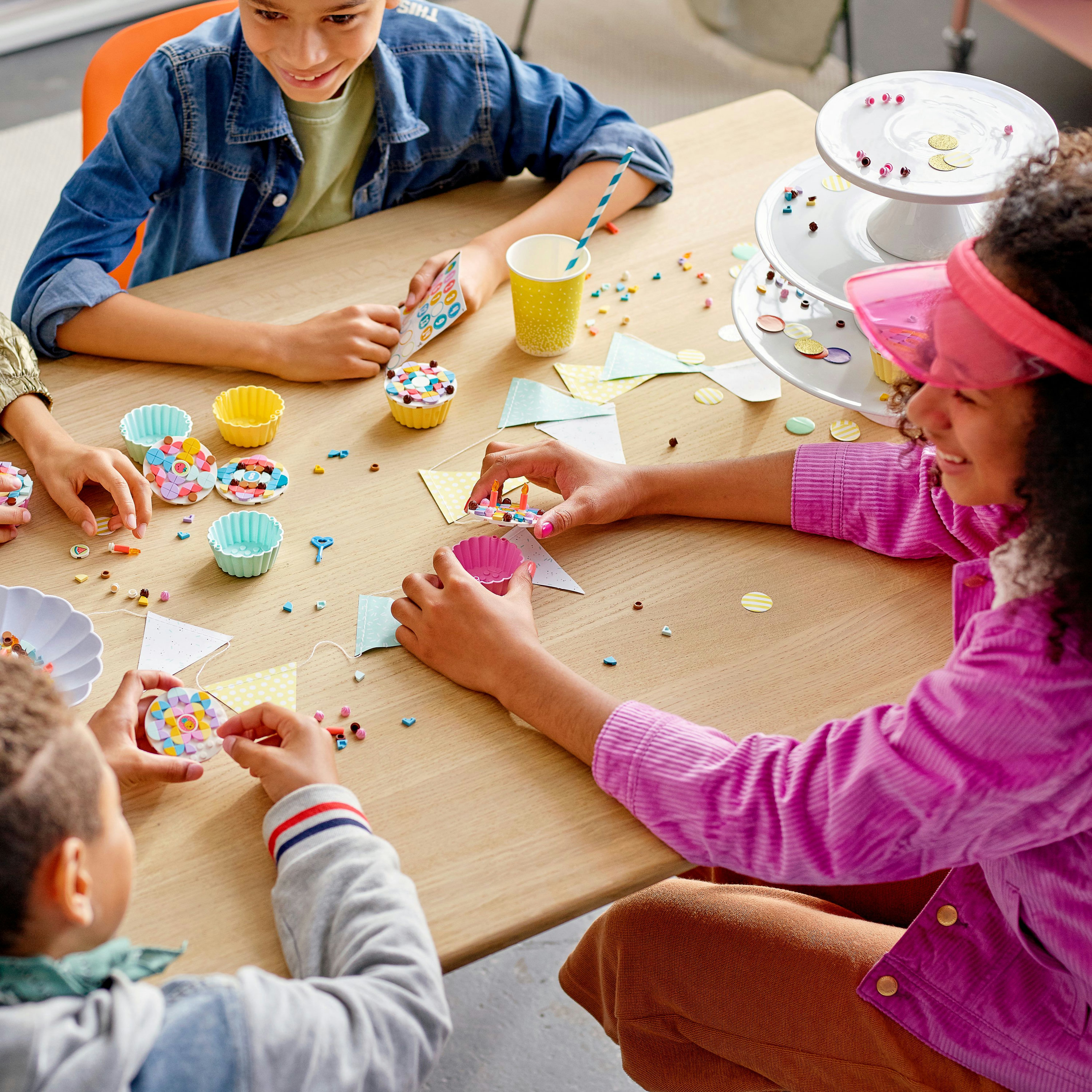 Kinder dekorieren Cupcakes mit Lego. Tisch mit Cupcakes und Dekorationen.