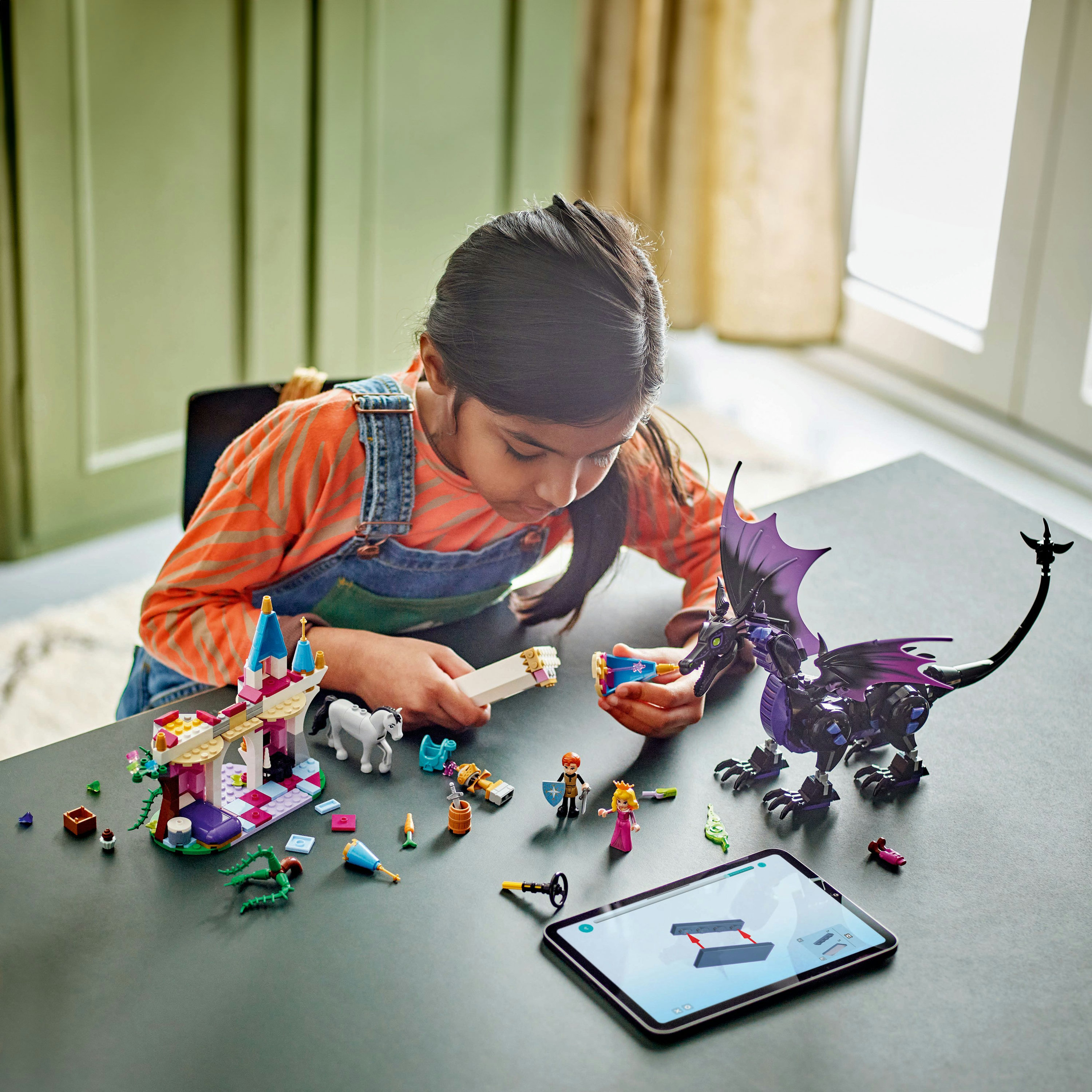 Niña jugando con un set LEGO con un dragón y un castillo. Incluye varias figuras y accesorios.