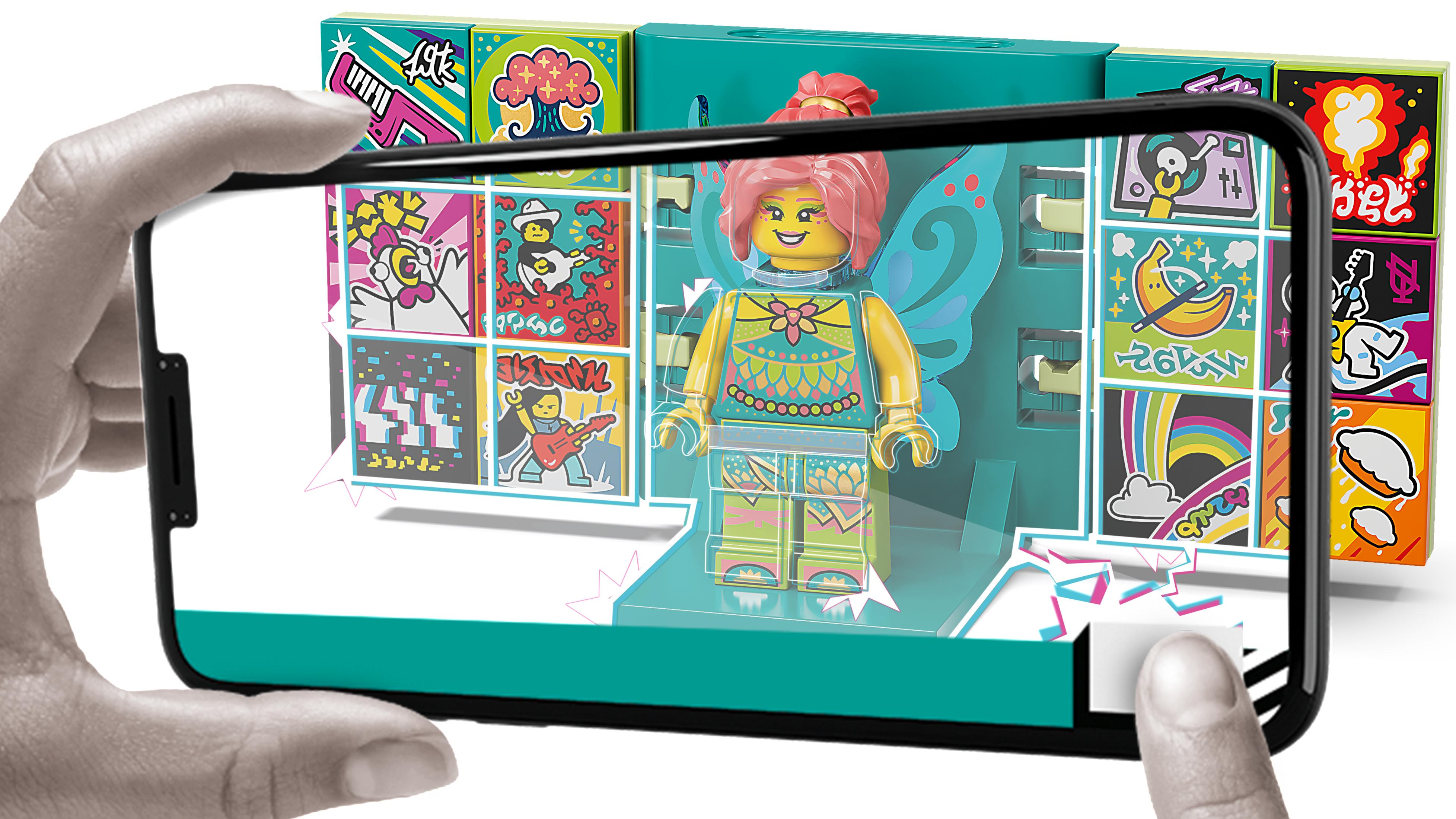 Osoba trzyma telefon z figurką Lego, zestaw kolorowych klocków Lego wokół niej.