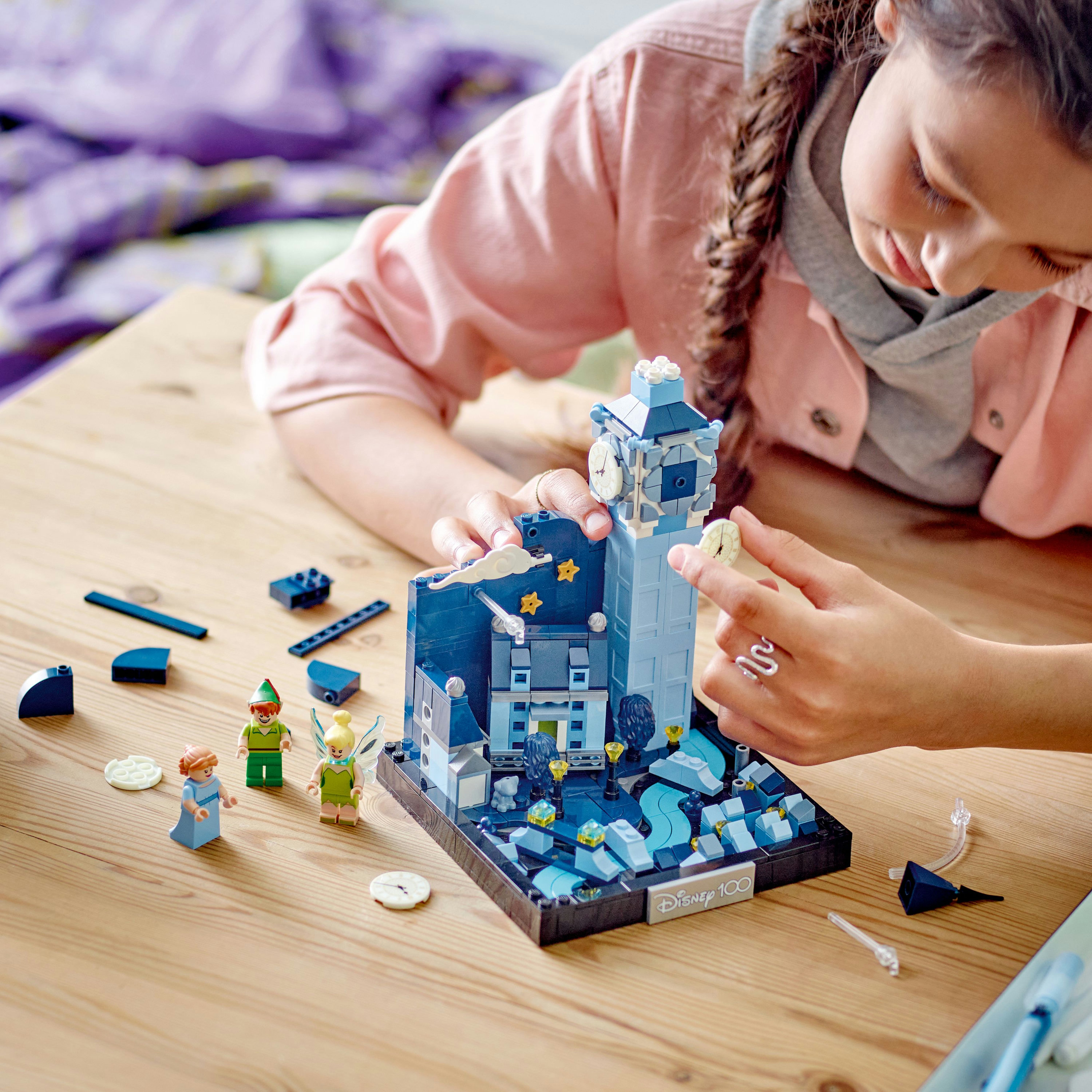 Een kind dat een LEGO-set van een klokkentoren en elfenfiguren in elkaar zet.