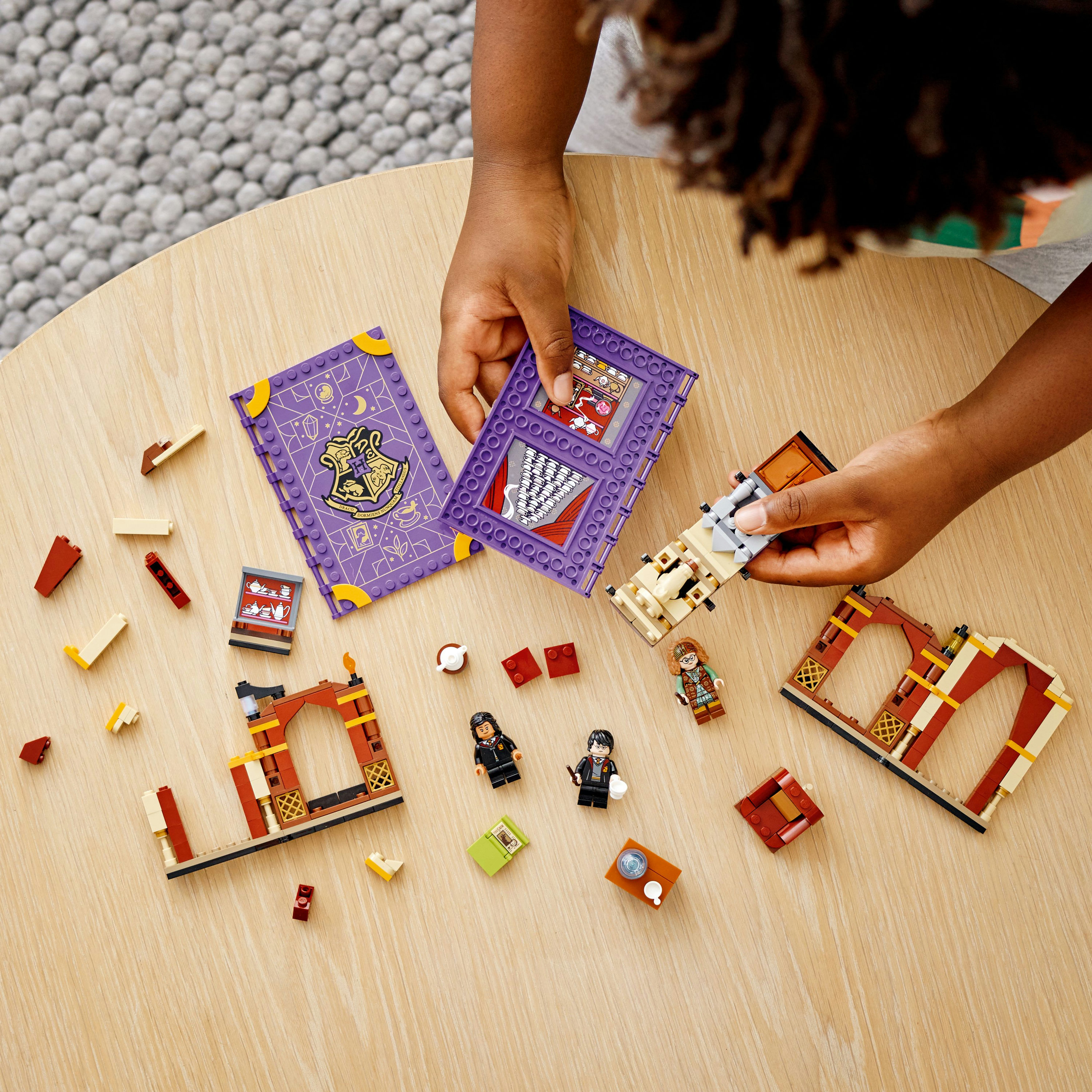 Kind baut Lego Harry Potter Set mit Figuren und einem lila Buch zusammen.