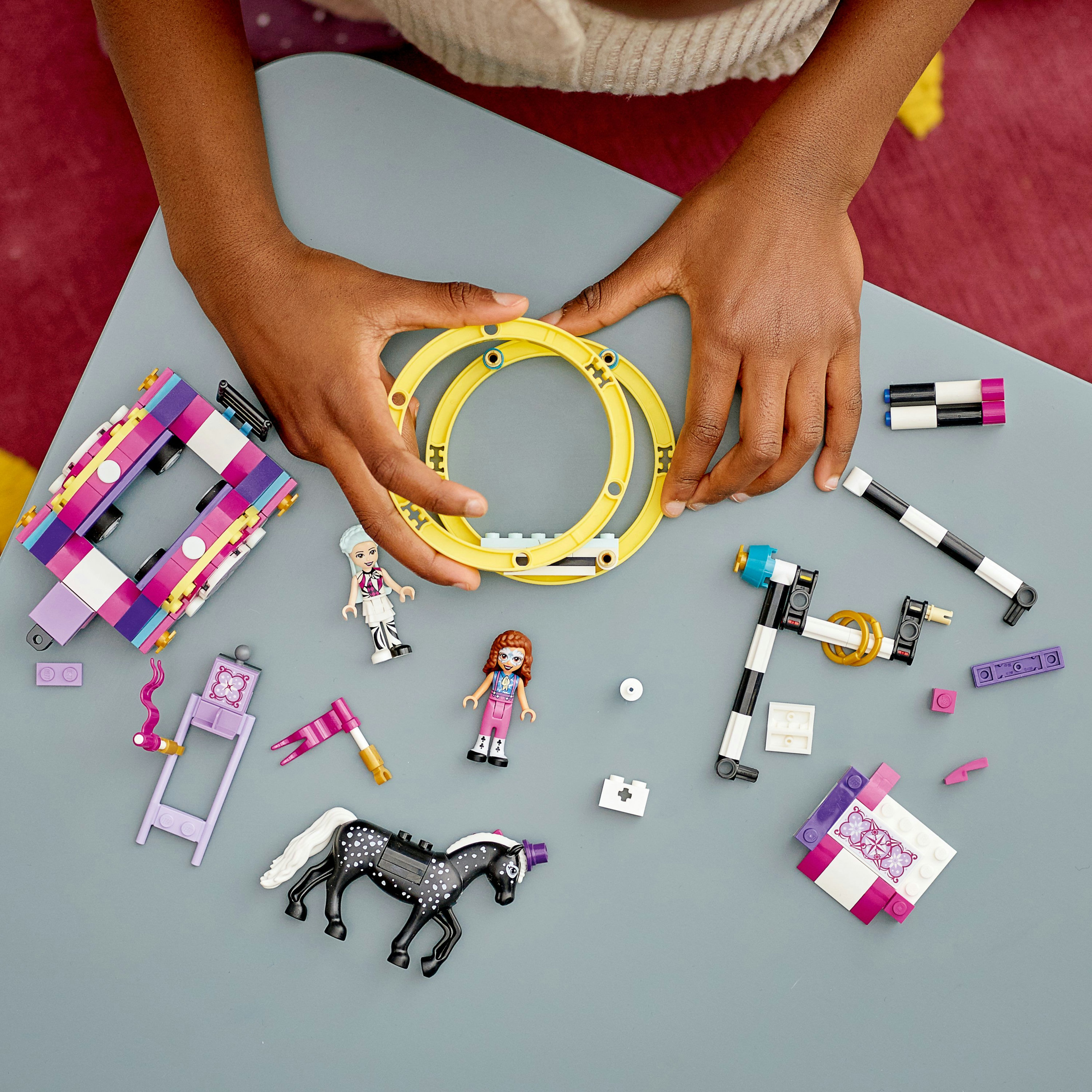 Un bambino gioca con i giocattoli Lego Friends su una superficie grigia.