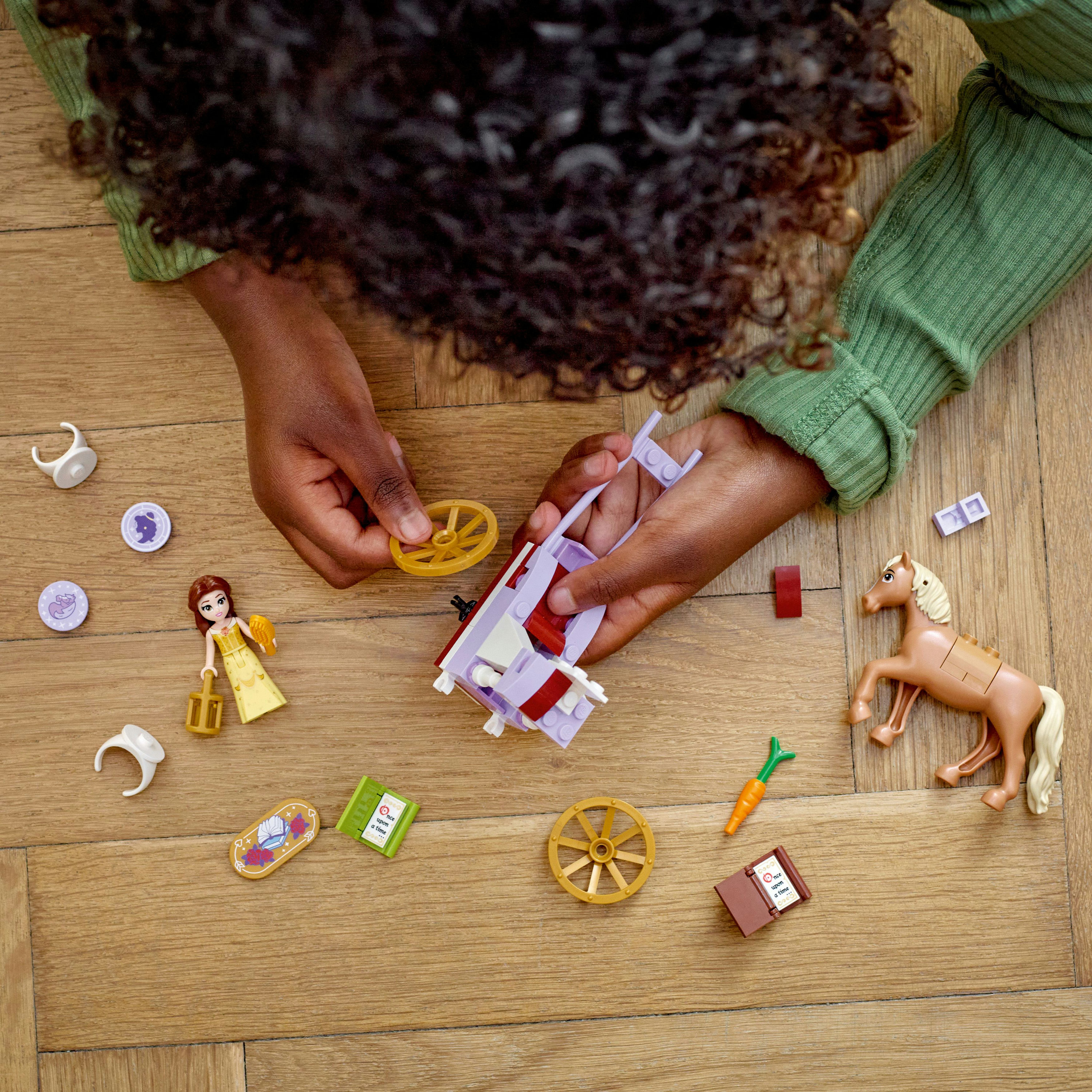Hände montieren ein Lego Friends Set mit Kutsche, Pferd und Minifiguren.