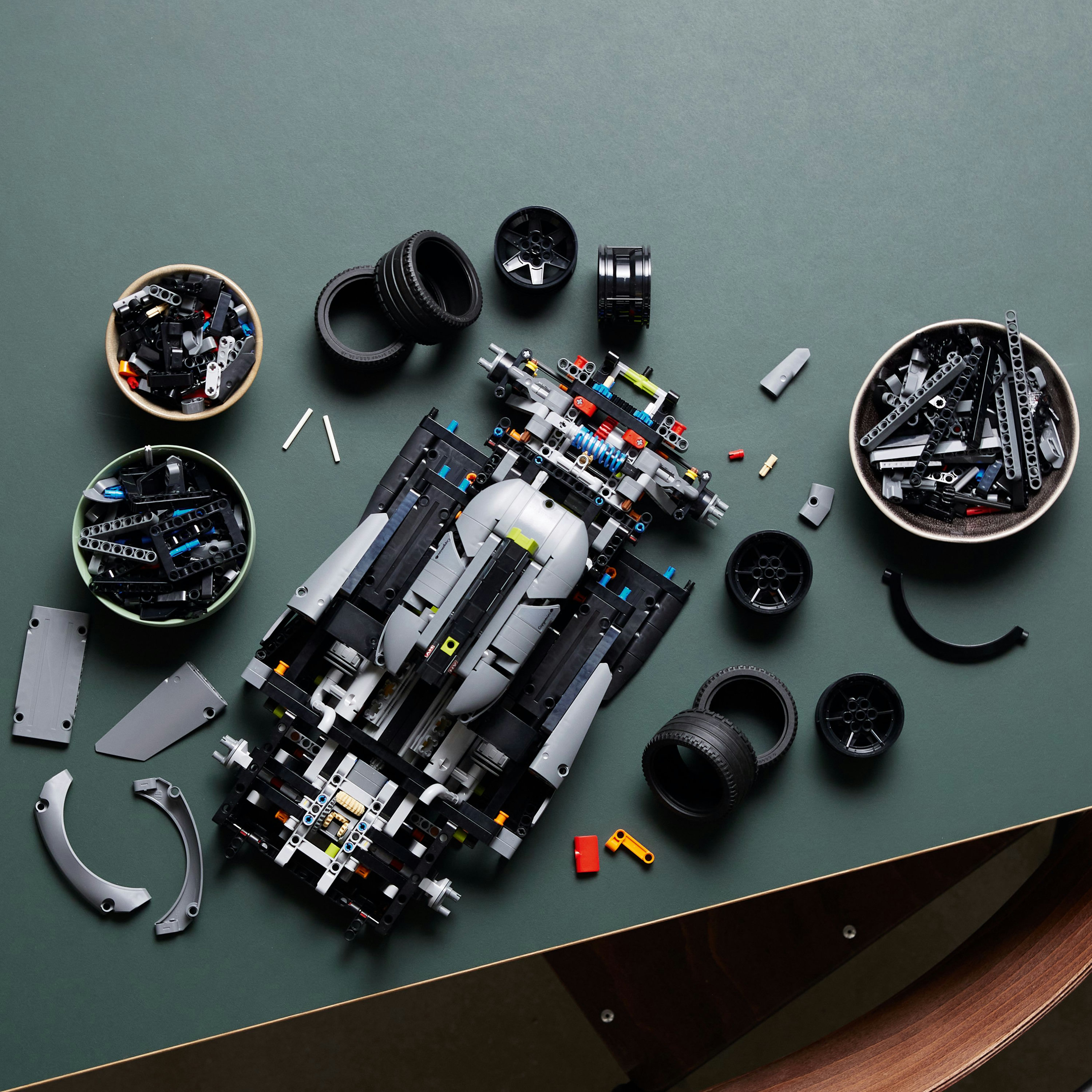 Części samochodowe i opony Lego ułożone z karoserią w trakcie montażu na zielonej powierzchni.