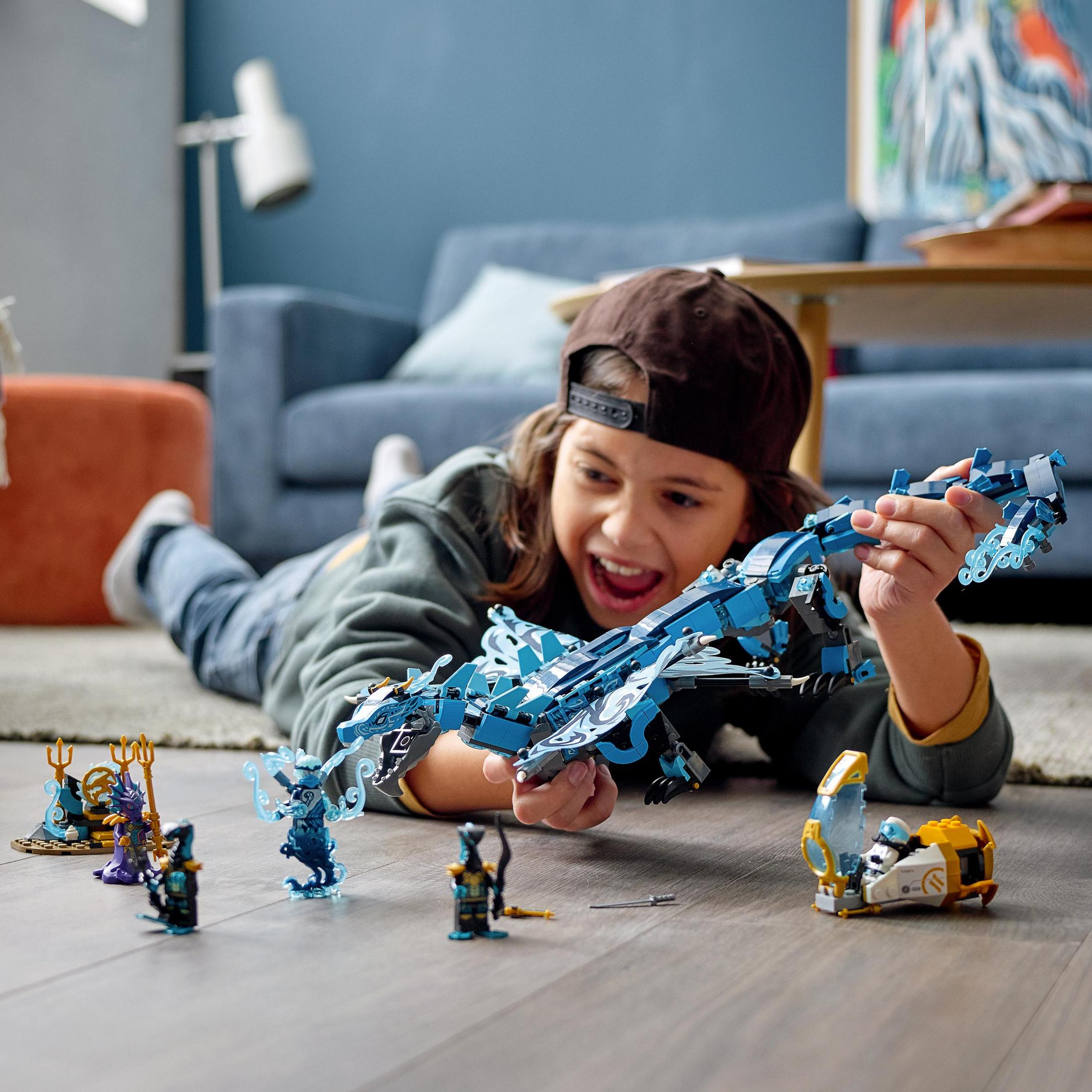 Un bambino che gioca con un set di draghi Lego Ninjago sul pavimento.