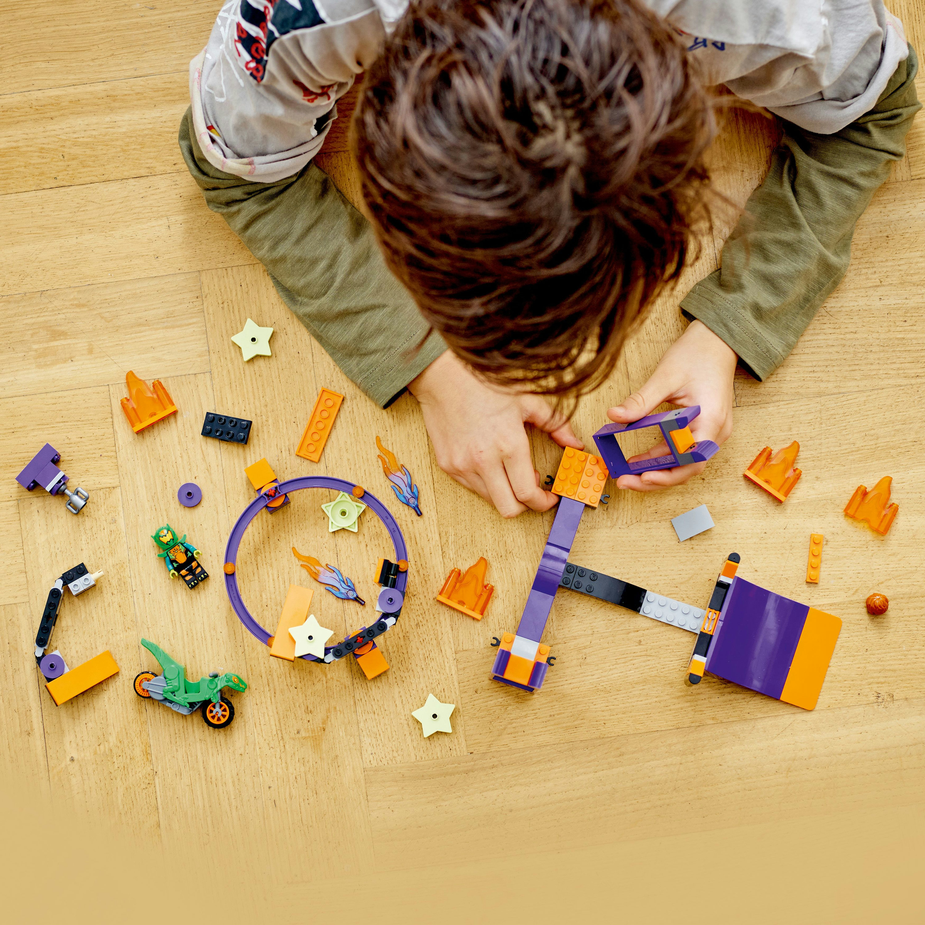 Een kind speelt met verschillende Lego stukken, waaronder een motor en een kraan.