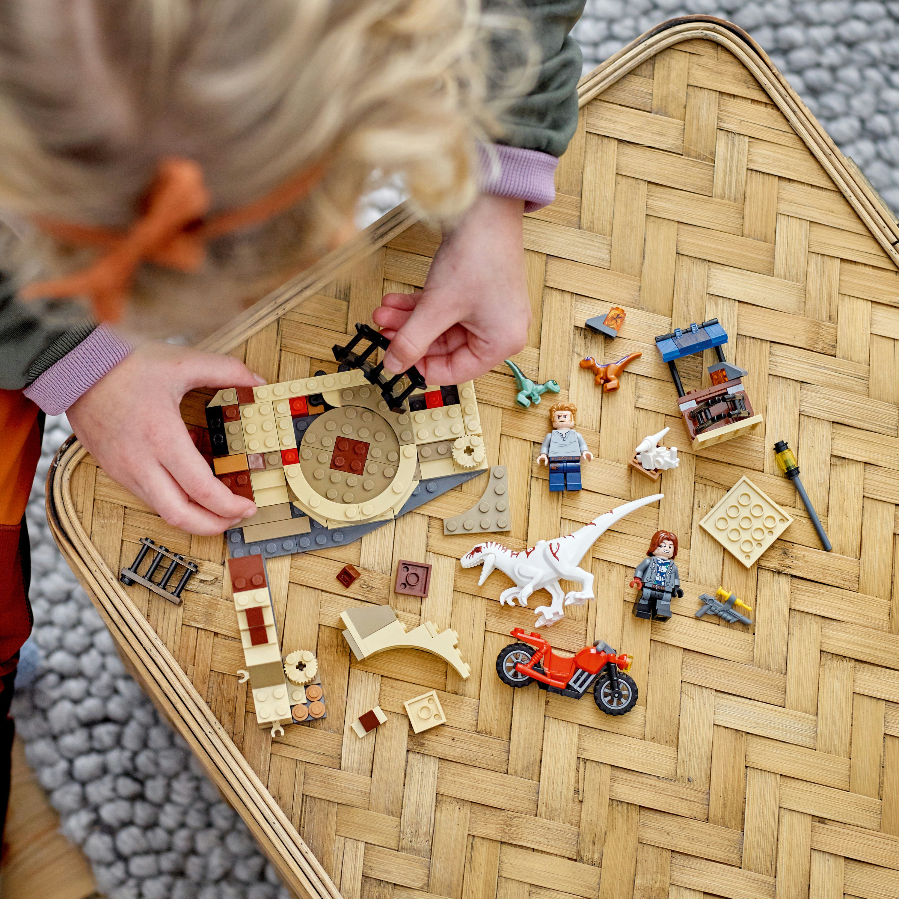 Enfant jouant avec des briques Lego sur une table tissée. Ensembles, figurines et une moto.