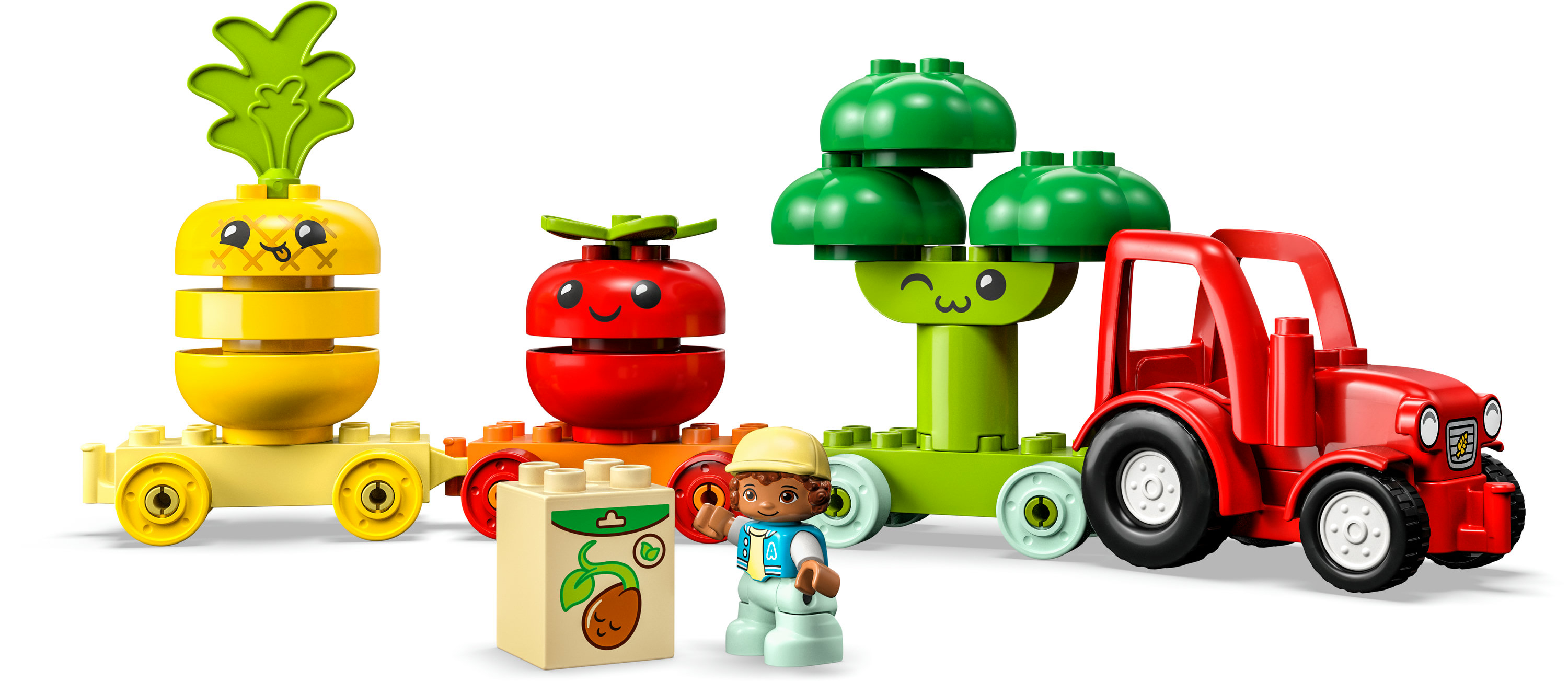 Set Lego Duplo con un trattore rosso, una figura di ragazzo e strutture a tema vegetale, tra cui una carota.