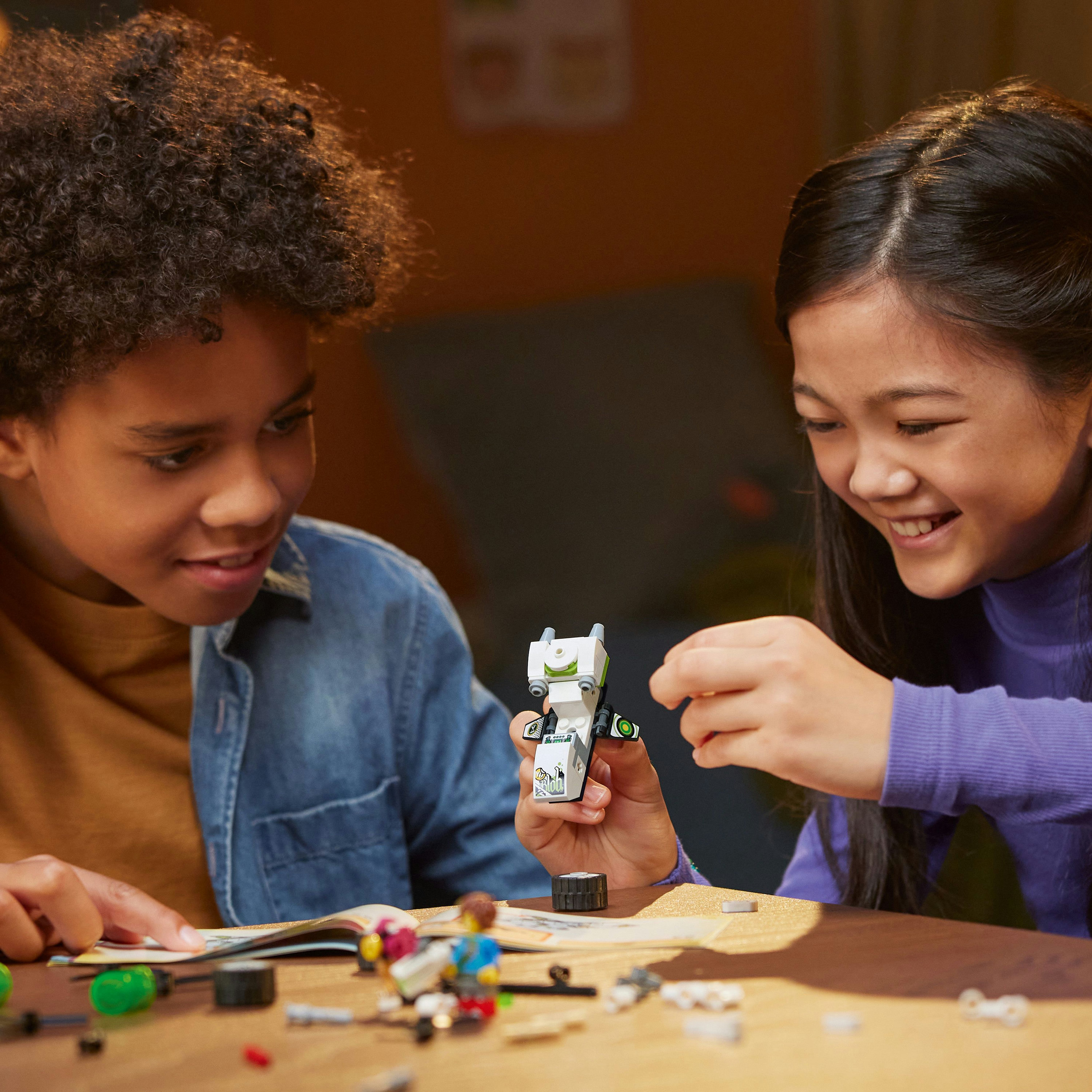 Zwei Kinder bauen mit Lego, eines hält einen kleinen Lego-Roboter.