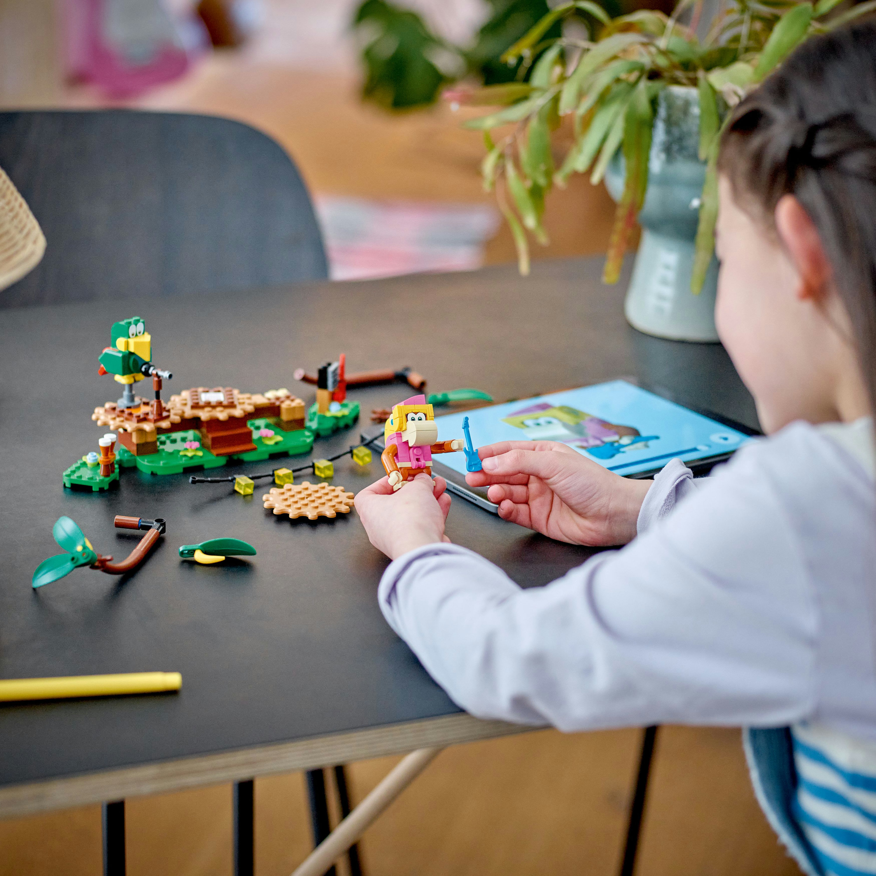 Kind speelt met Lego set, bouwstenen, groene en bruine stukken.