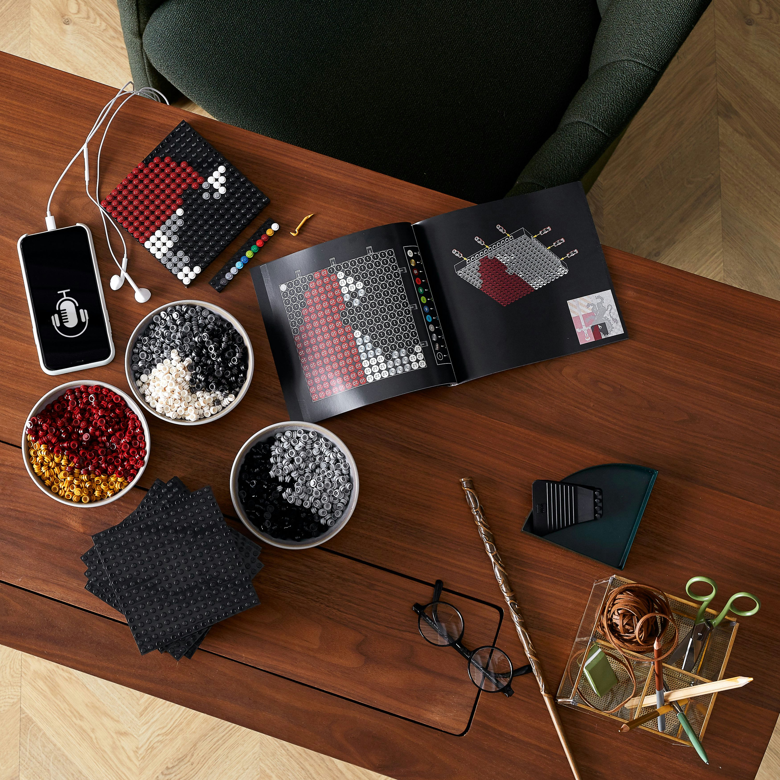 LEGO building in progress with components. A phone and other accessories are on a wooden surface.