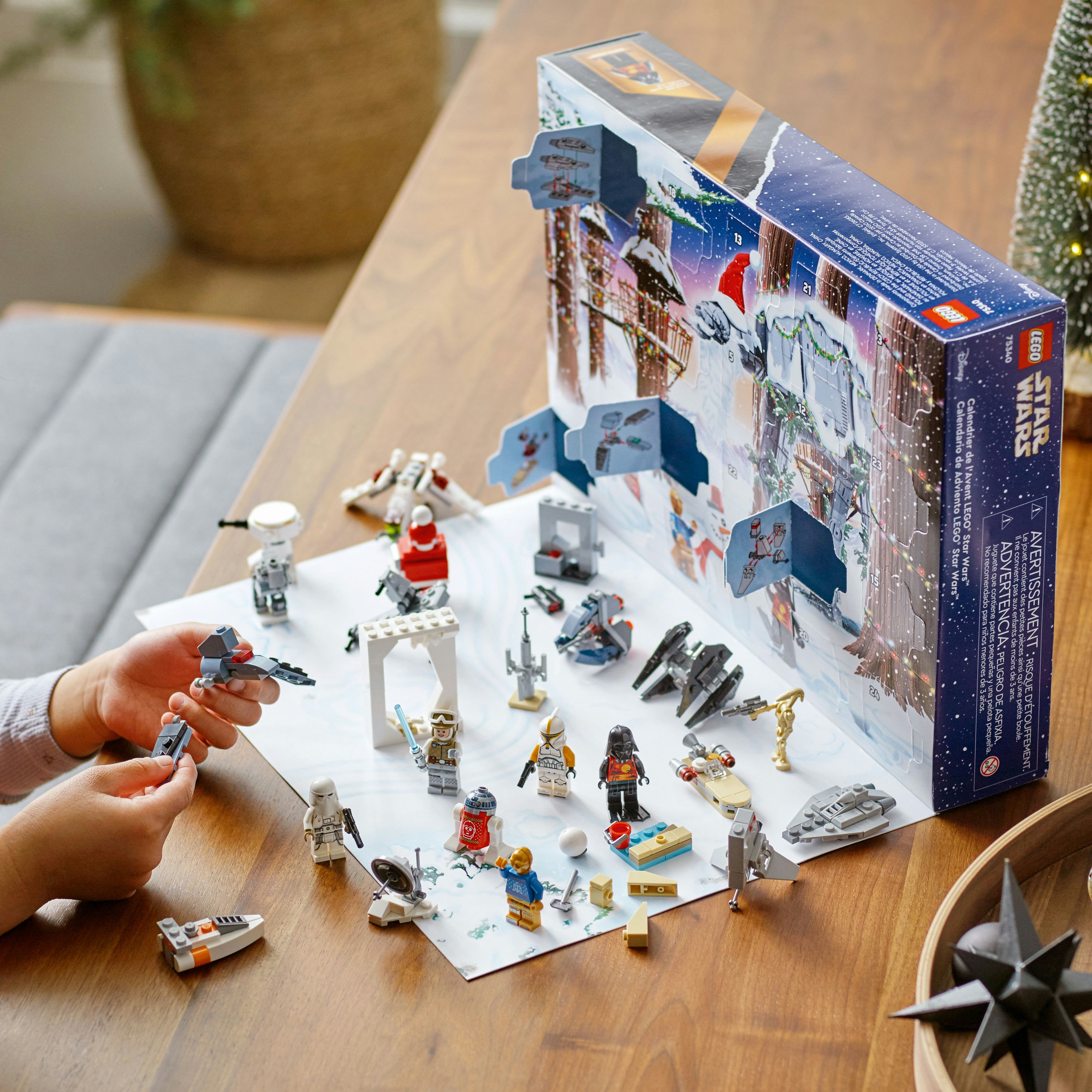 Lego Star Wars advent takvimi, figürler ve küçük yapılar ahşap bir masada. Bir çocuğun elleri.