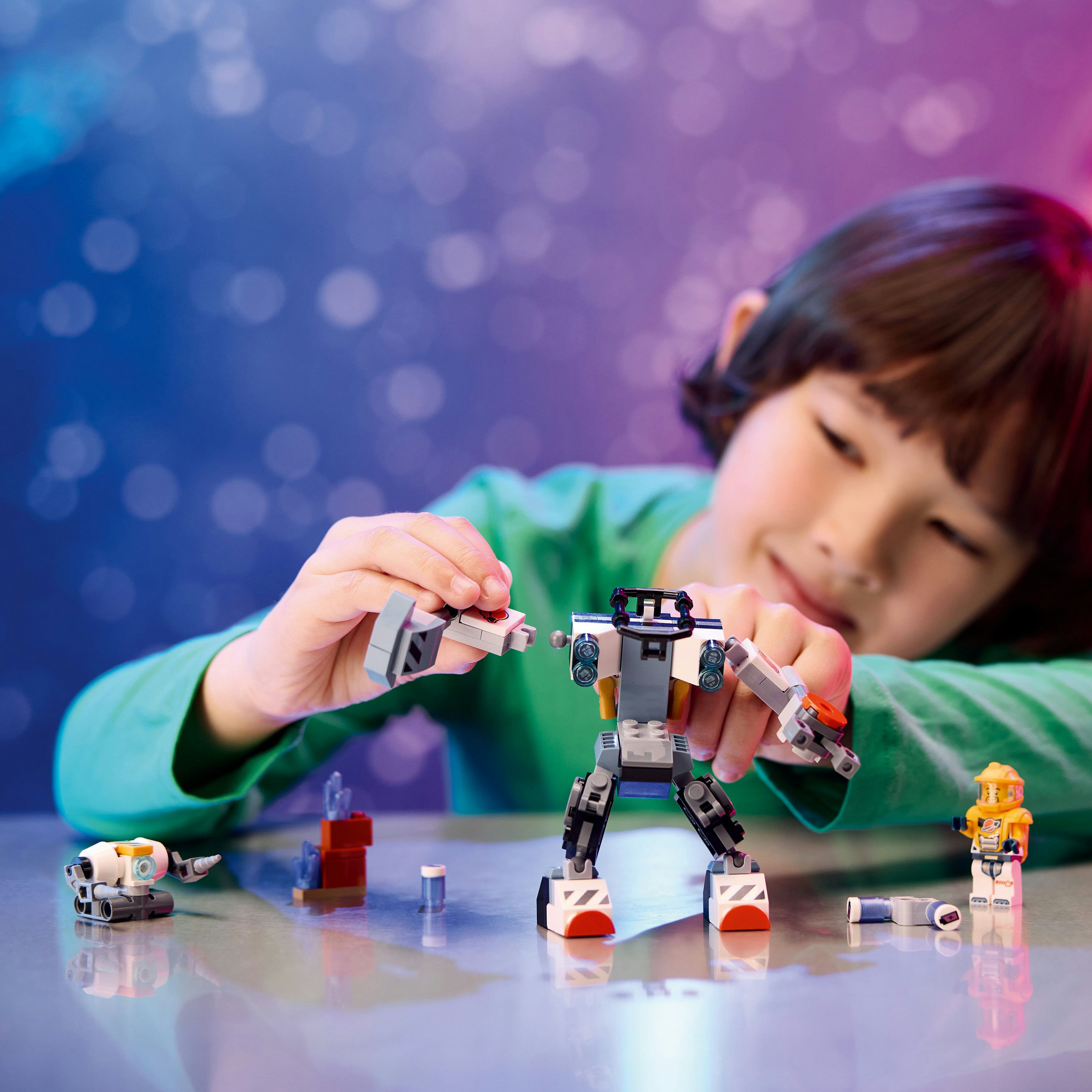 Lego robotuyla oynayan bir çocuk. Çocuk gülümsüyor ve robot çoğunlukla gri ve beyaz.