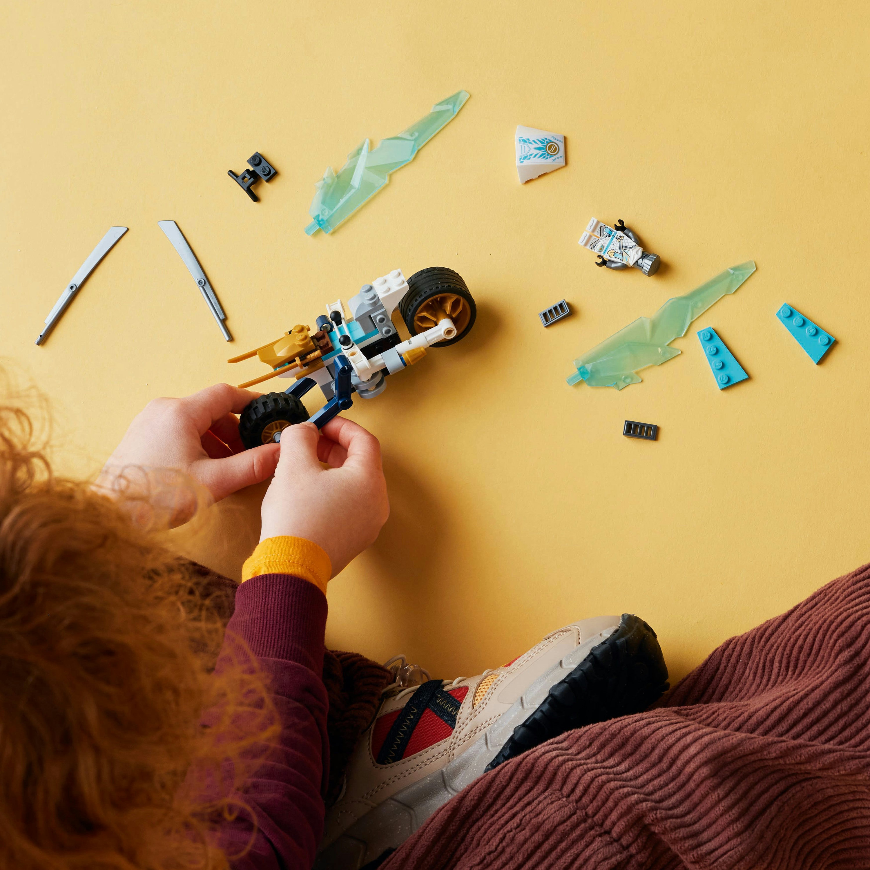 Kinderhände bauen ein Lego-Motorrad zusammen. Lego-Teile und Zubehör sind verstreut.
