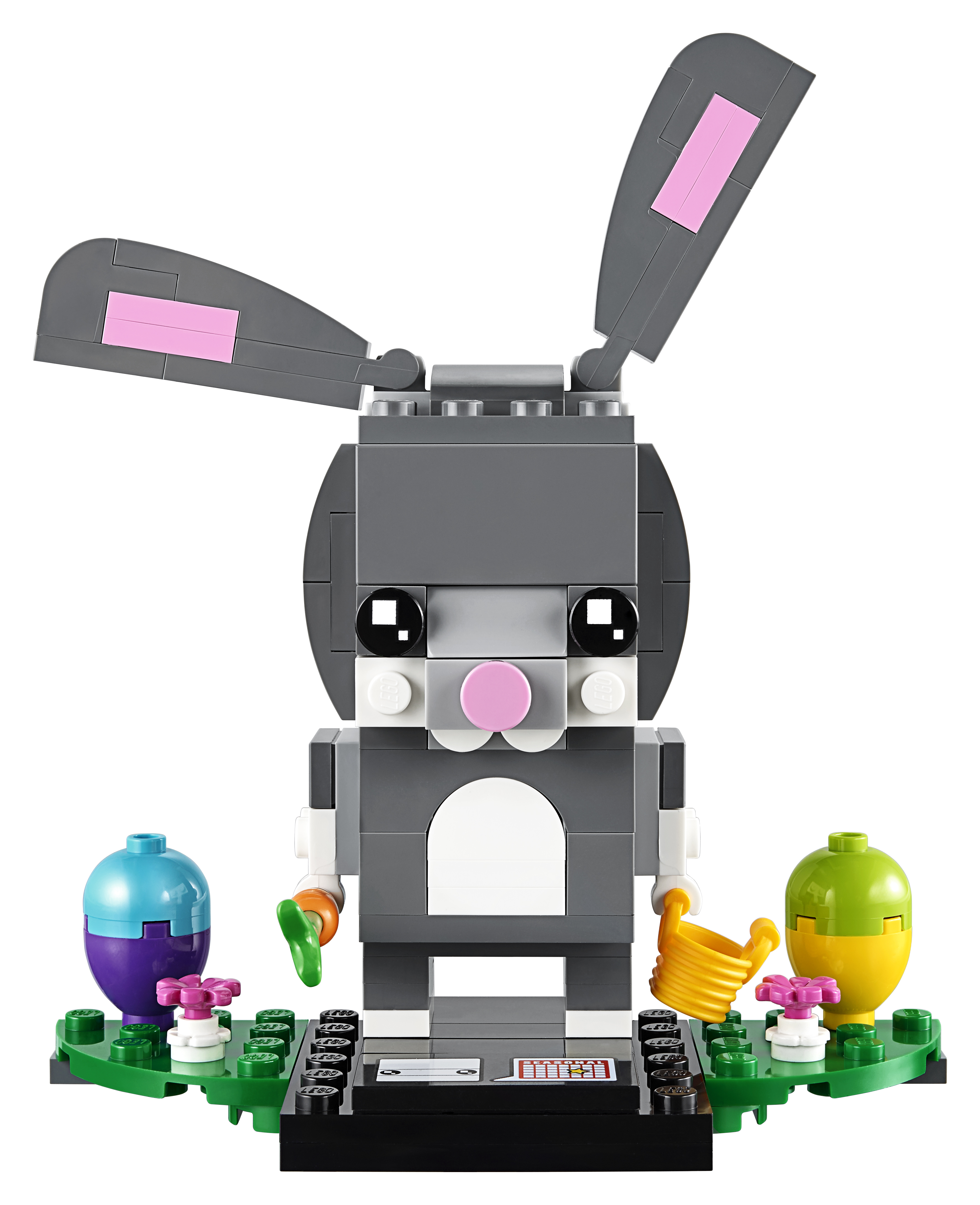 Ein Lego-Osterhase mit Karotte und Ostereiern auf grüner Basis. Weißer Hintergrund.