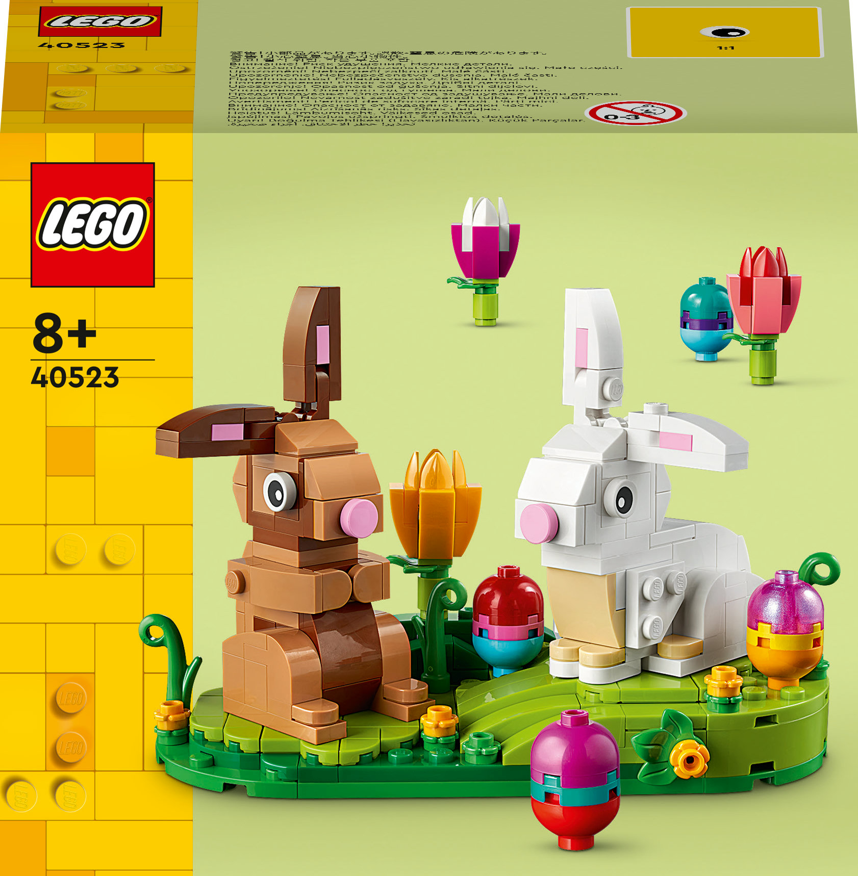 Bir Lego seti, iki Lego tavşanı, çiçekler ve Paskalya yumurtalarıyla çevrili, yeşil bir taban üzerinde, sarı bir arka planla gösteriyor.