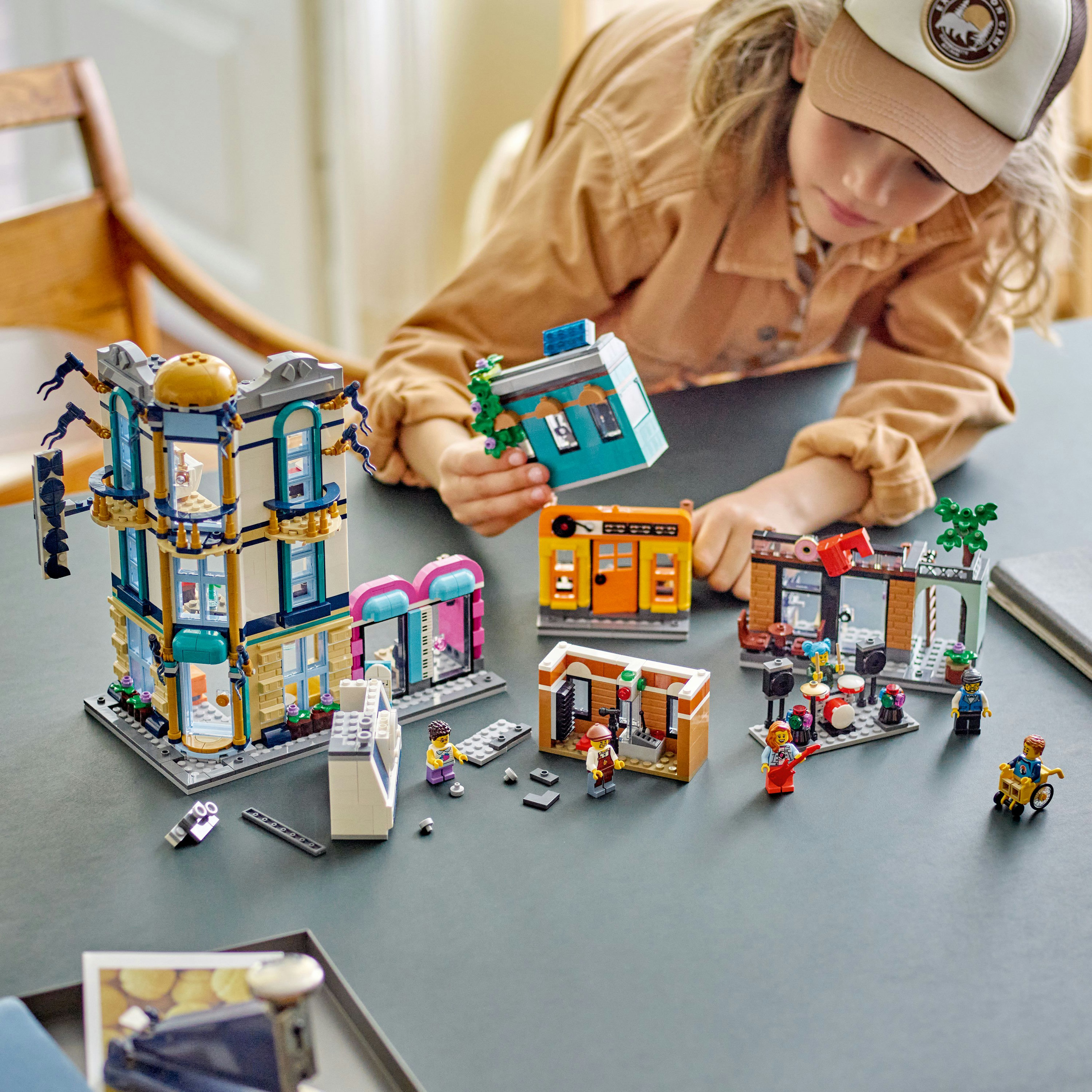 Een kind speelt met Lego. De set heeft meerdere mini-gebouwen, figuren en accessoires.